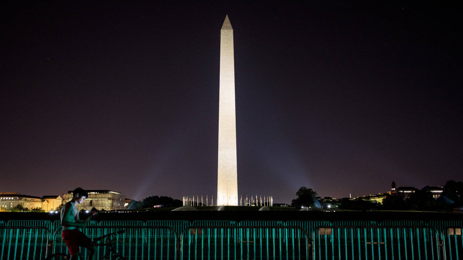 Washington Monument 桌布 壁紙 — 一名孤獨的自行車騎士在星空下於發光的華盛頓紀念碑旁夜間稍作停留。