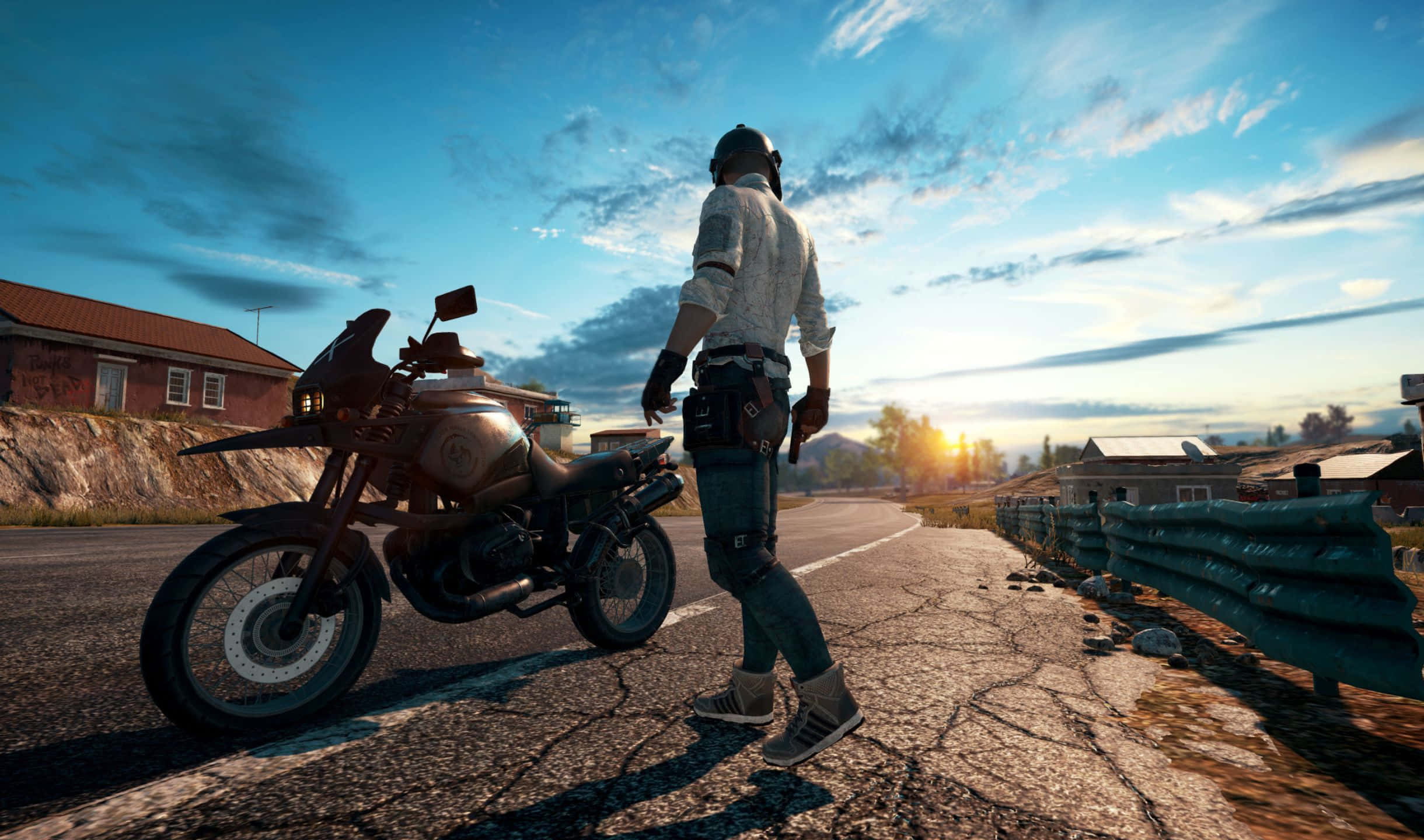 2440x1440 Playerunknown's Battlegrounds 桌布 壁紙 — 一名孤獨的騎士身穿戰術裝備，在夕陽下站在崎嶇摩托車旁，背景是一個小村莊。