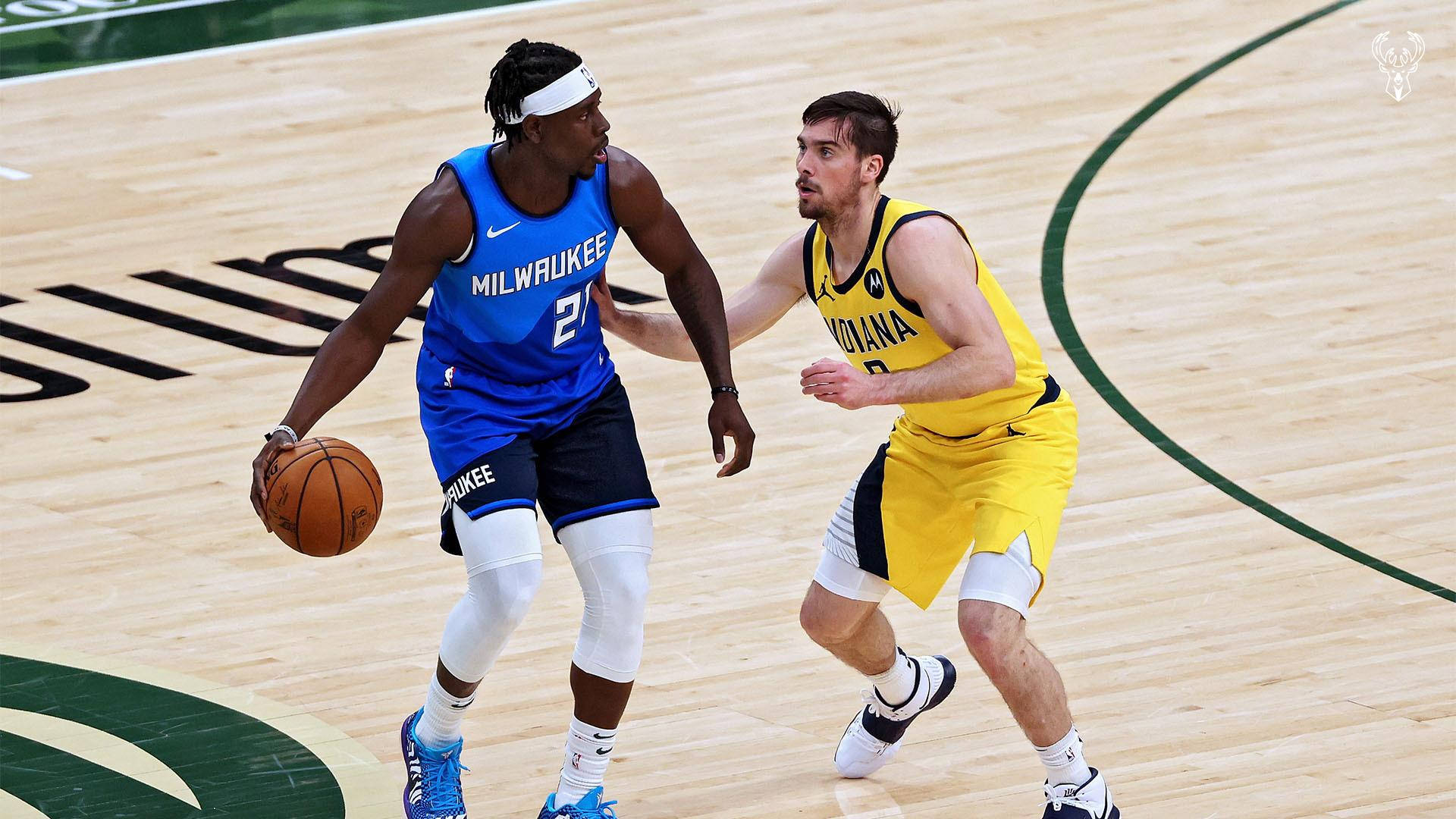 Jrue Holiday 桌布 壁紙 — 一名密爾瓦基公鹿球員在拋光籃球場上運球，同時被印第安納溜馬球員緊密防守。