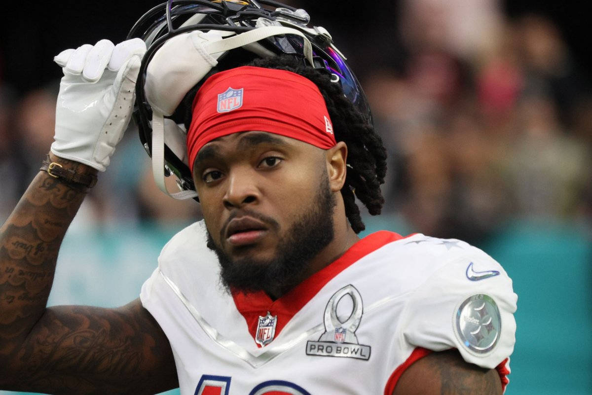 匹茲堡鋼人 桌布 壁紙 — 一名專注的NFL球員身穿白色Pro Bowl球衣，舉起頭盔，露出紅色頭帶和刺青手臂。