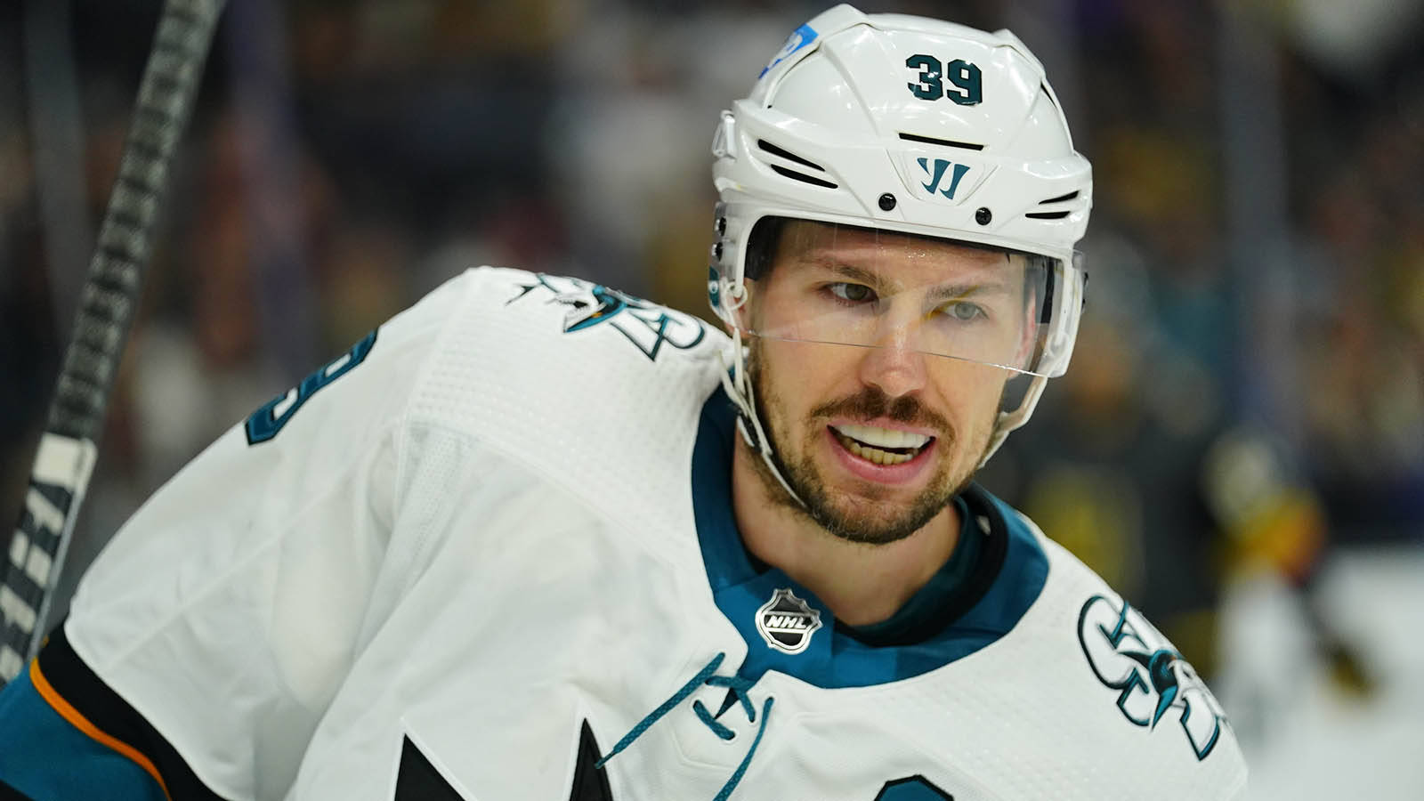 hockey 桌布 壁紙 — 一名專注的冰球運動員穿著白色Sharks球衣（號碼39）在比賽中在冰上向前傾。