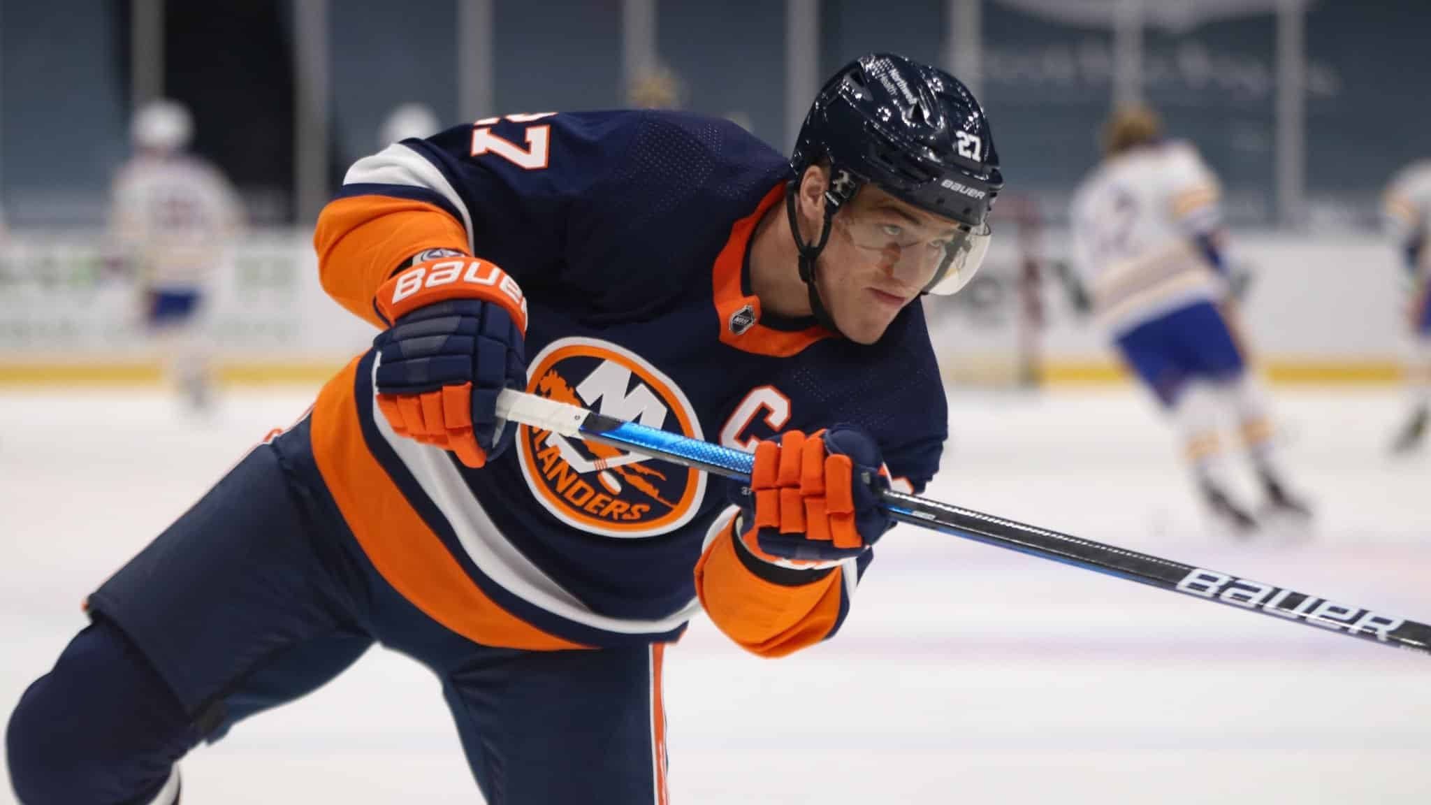 hockey 桌布 壁紙 — 一名專注的冰球運動員身穿埃德蒙頓油人隊球衣，在比賽中俯身握緊球棍在冰面上。