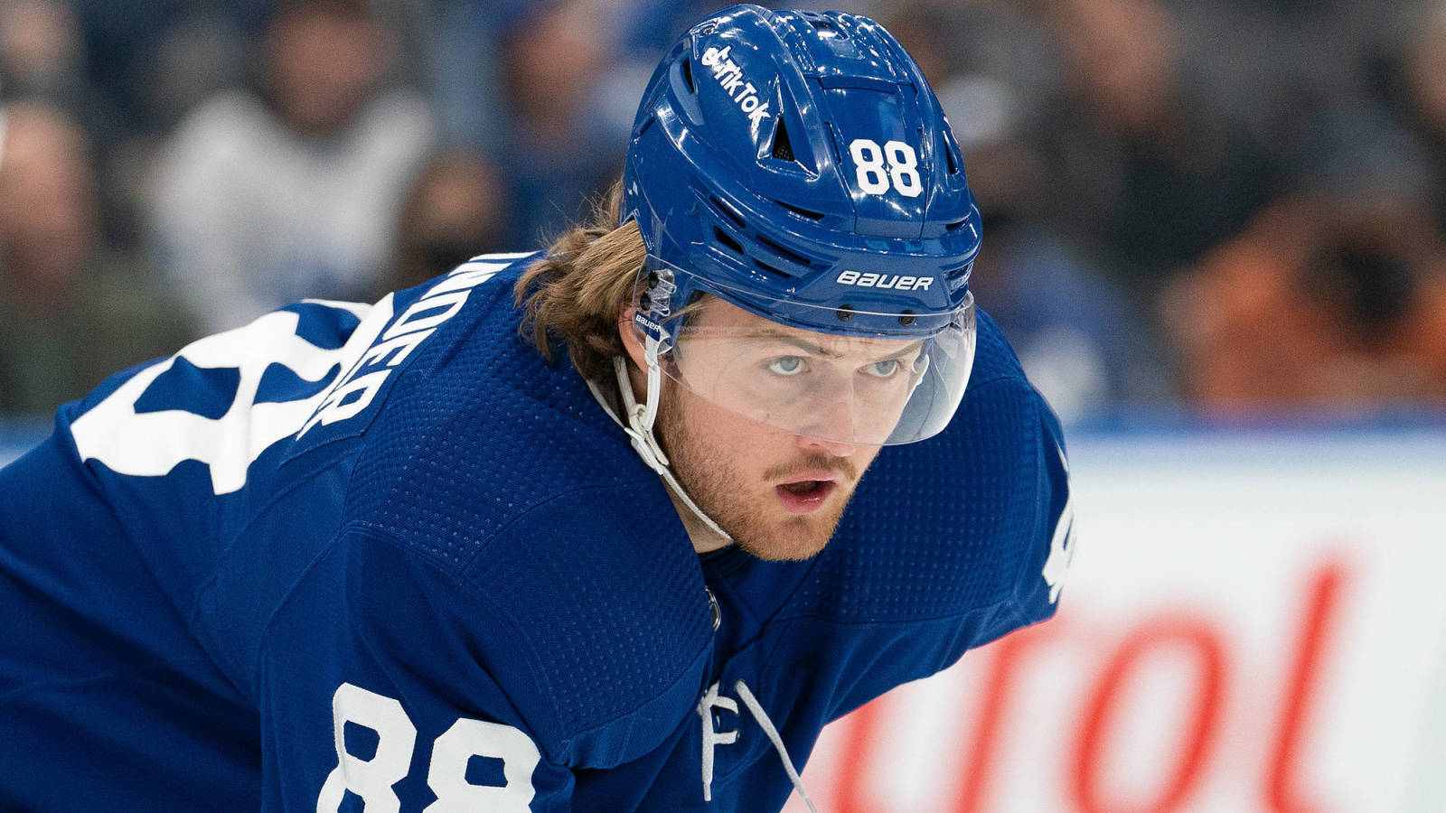 hockey 桌布 壁紙 — 一名專注的冰球運動員身穿藍色多倫多楓葉隊球衣，在比賽中於冰上向前傾身。
