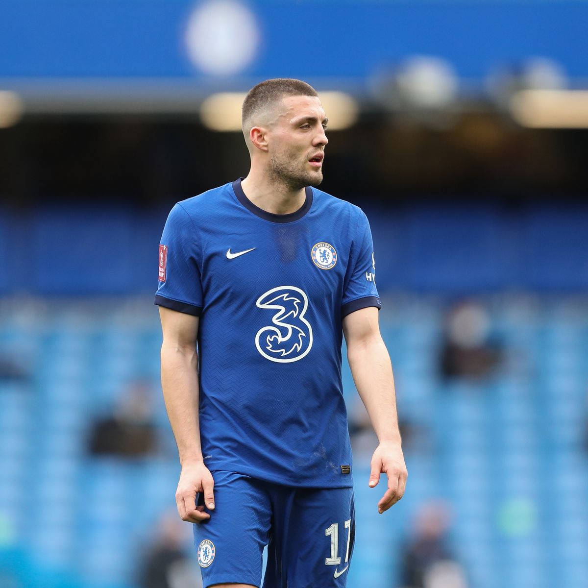 Football Players 桌布 壁紙 — 一名專注的切爾西足球員身穿藍色球衣，站在球場上，背後是模糊的看台。
