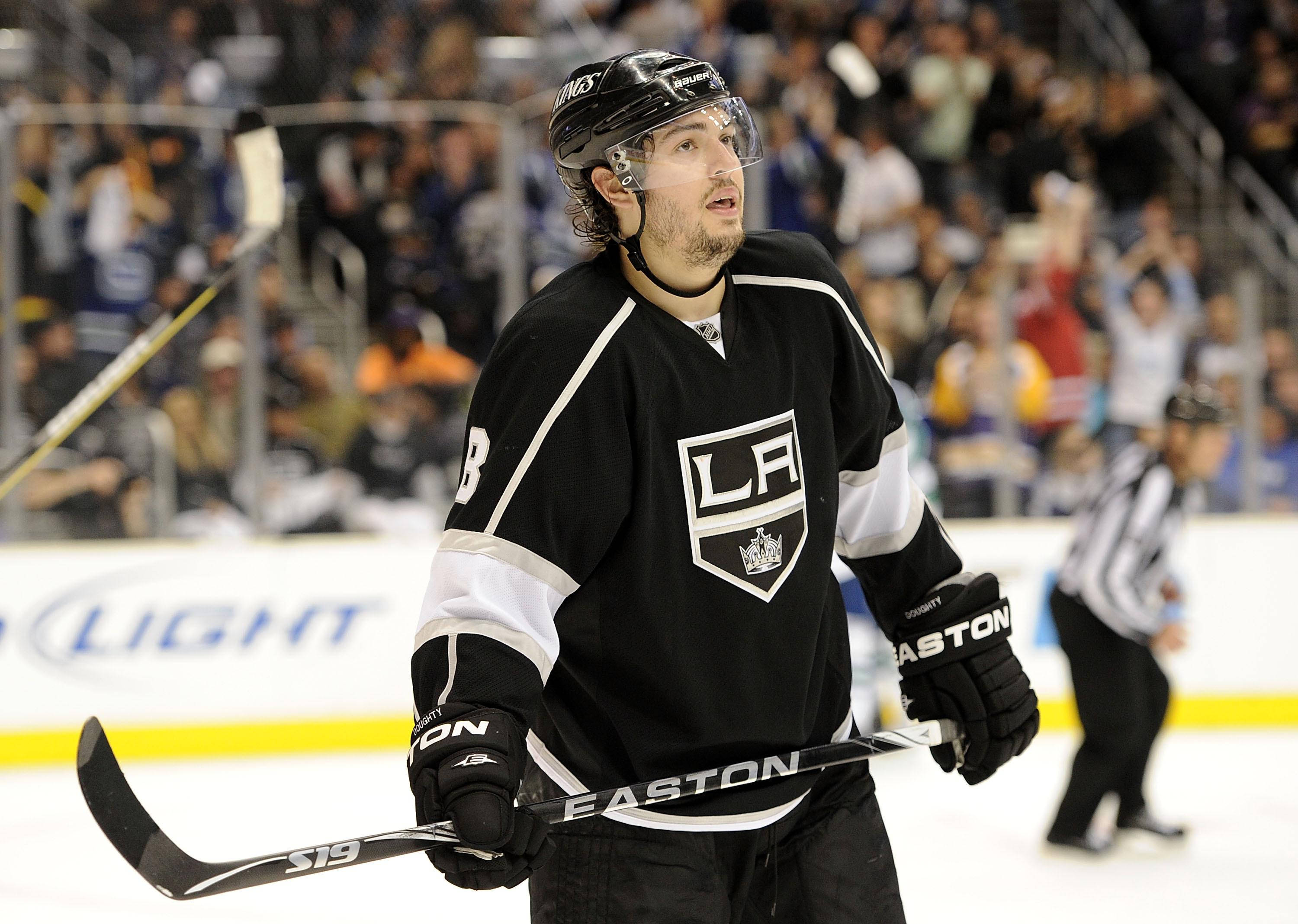 hockey 桌布 壁紙 — 一名專注的曲棍球球員身穿黑色LA Kings球衣，在冰上持棍比賽，背景有觀眾。