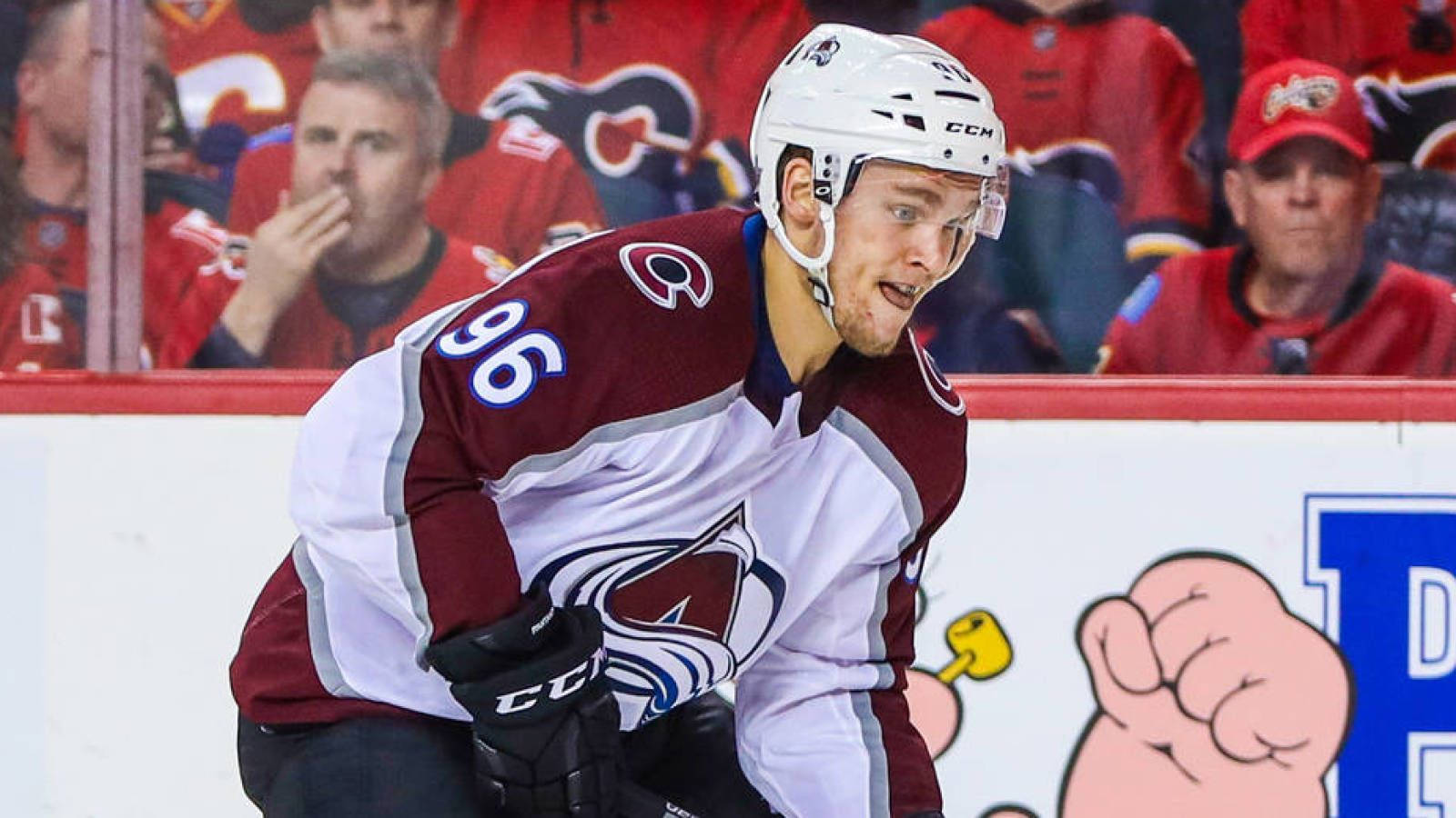 hockey 桌布 壁紙 — 一名專注的曲棍球運動員身穿栗色和白色制服，在比賽中帶著強烈的表情在冰上向前傾。