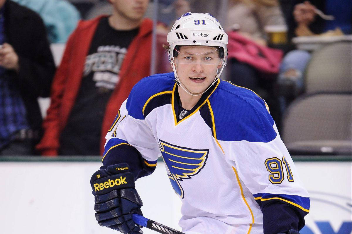 St Louis Blues 桌布 壁紙 — 一名專注的曲棍球運動員身穿白色、藍色和金色的91號球衣，在比賽中於冰上激烈滑行。