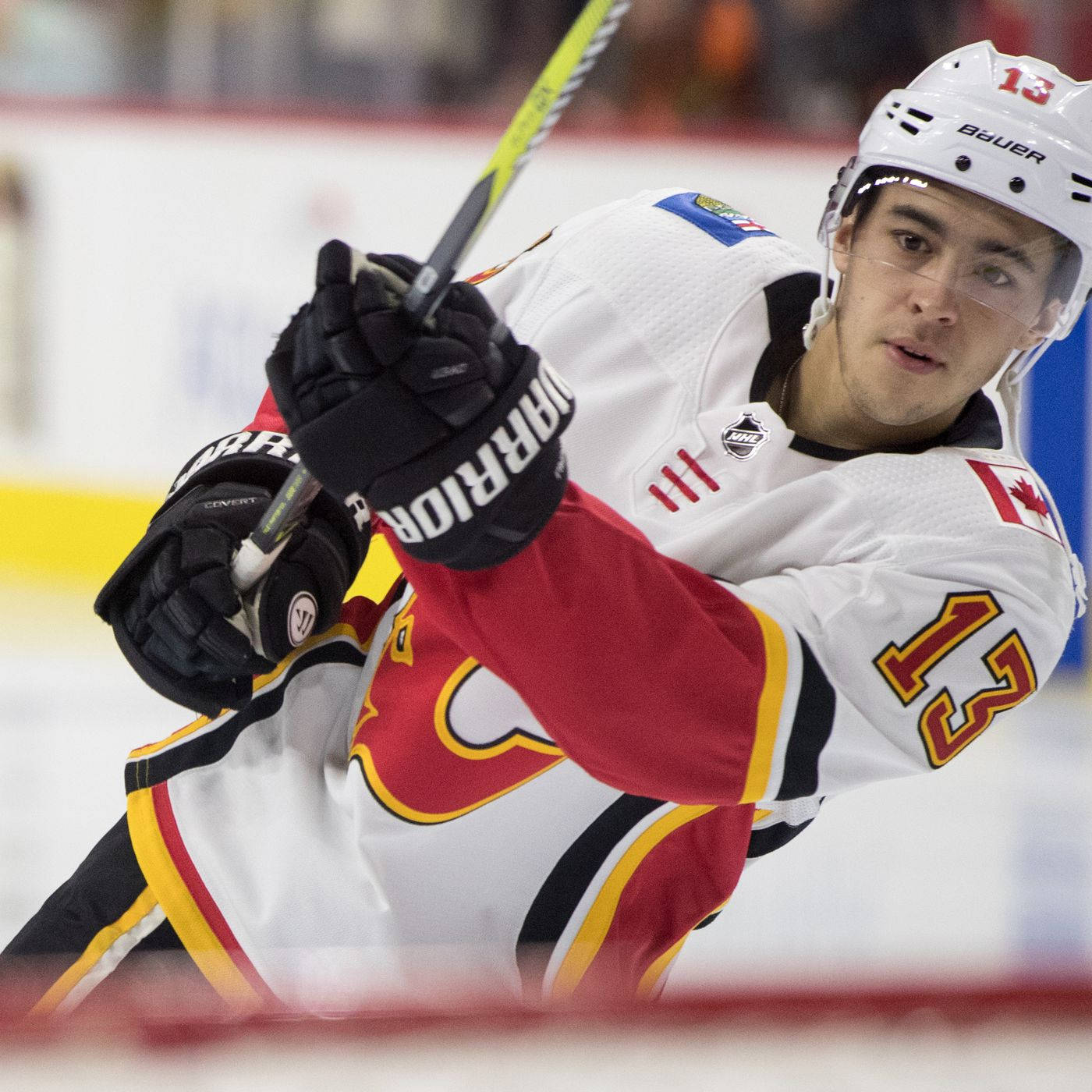 Johnny Gaudreau 桌布 壁紙 — 一名專注的曲棍球運動員身穿白色、紅色和黃色的Flames球衣，在冰場上向前傾身握著球桿。