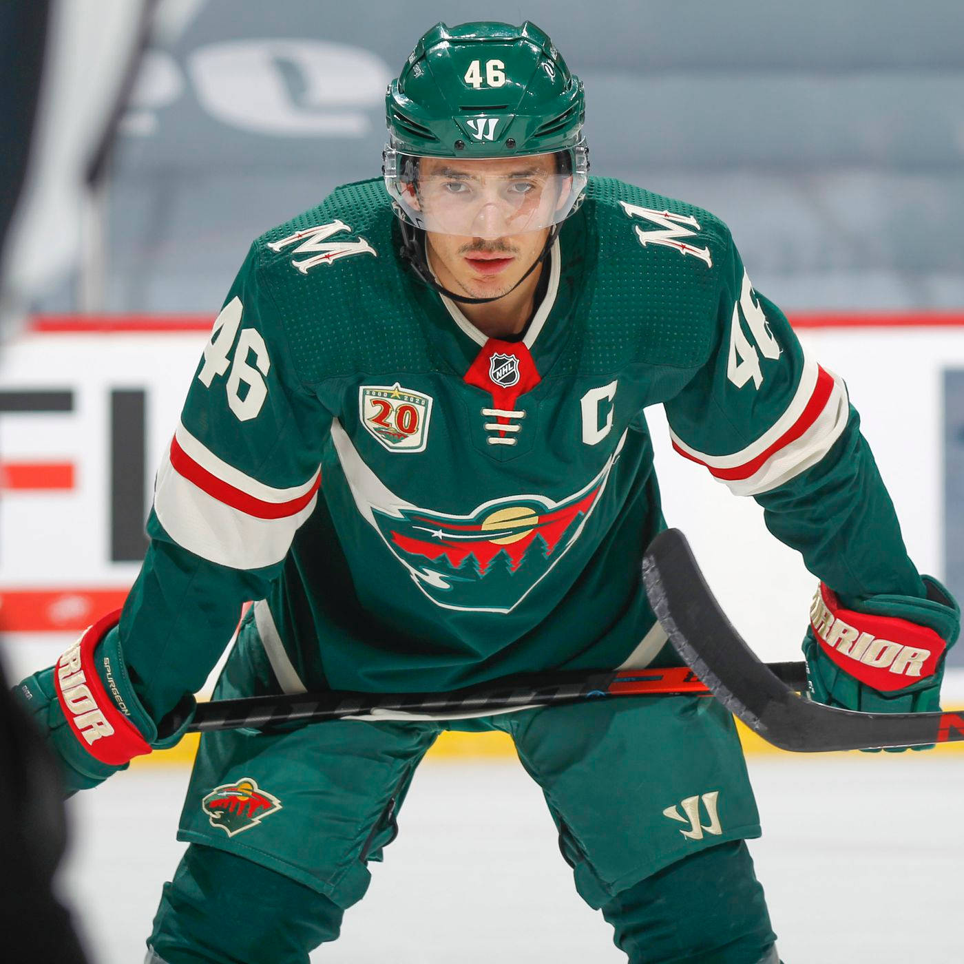 hockey 桌布 壁紙 — 一名專注的曲棍球運動員身穿綠色球衣46號，在比賽中蹲在冰上持桿。
