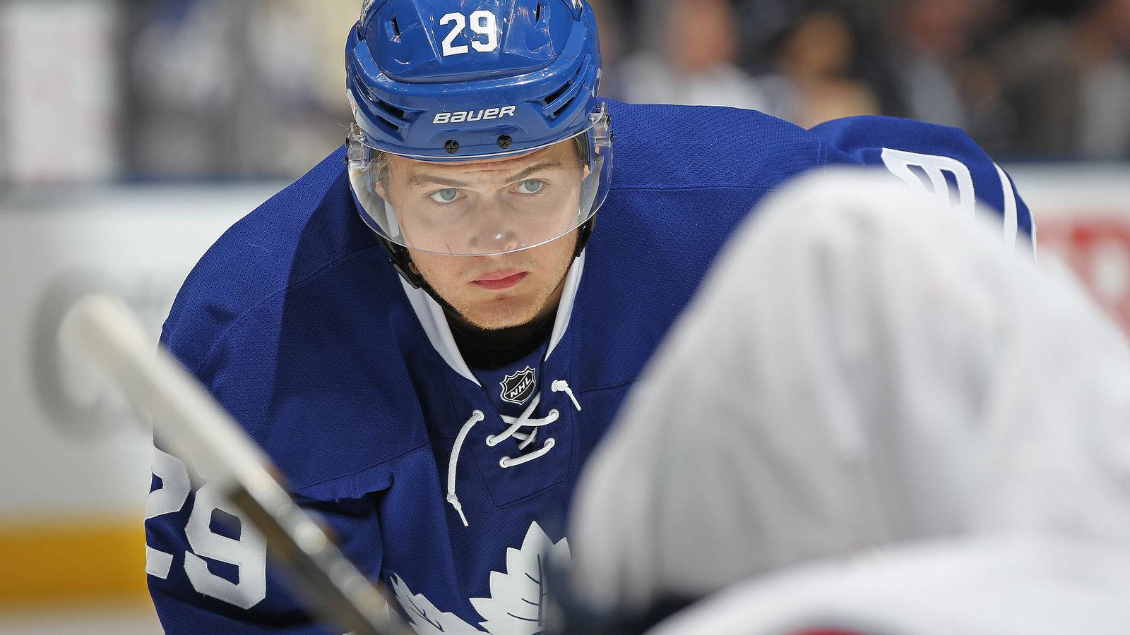hockey 桌布 壁紙 — 一名專注的曲棍球運動員身穿藍色多倫多楓葉隊球衣，在比賽中於冰上向前傾身。