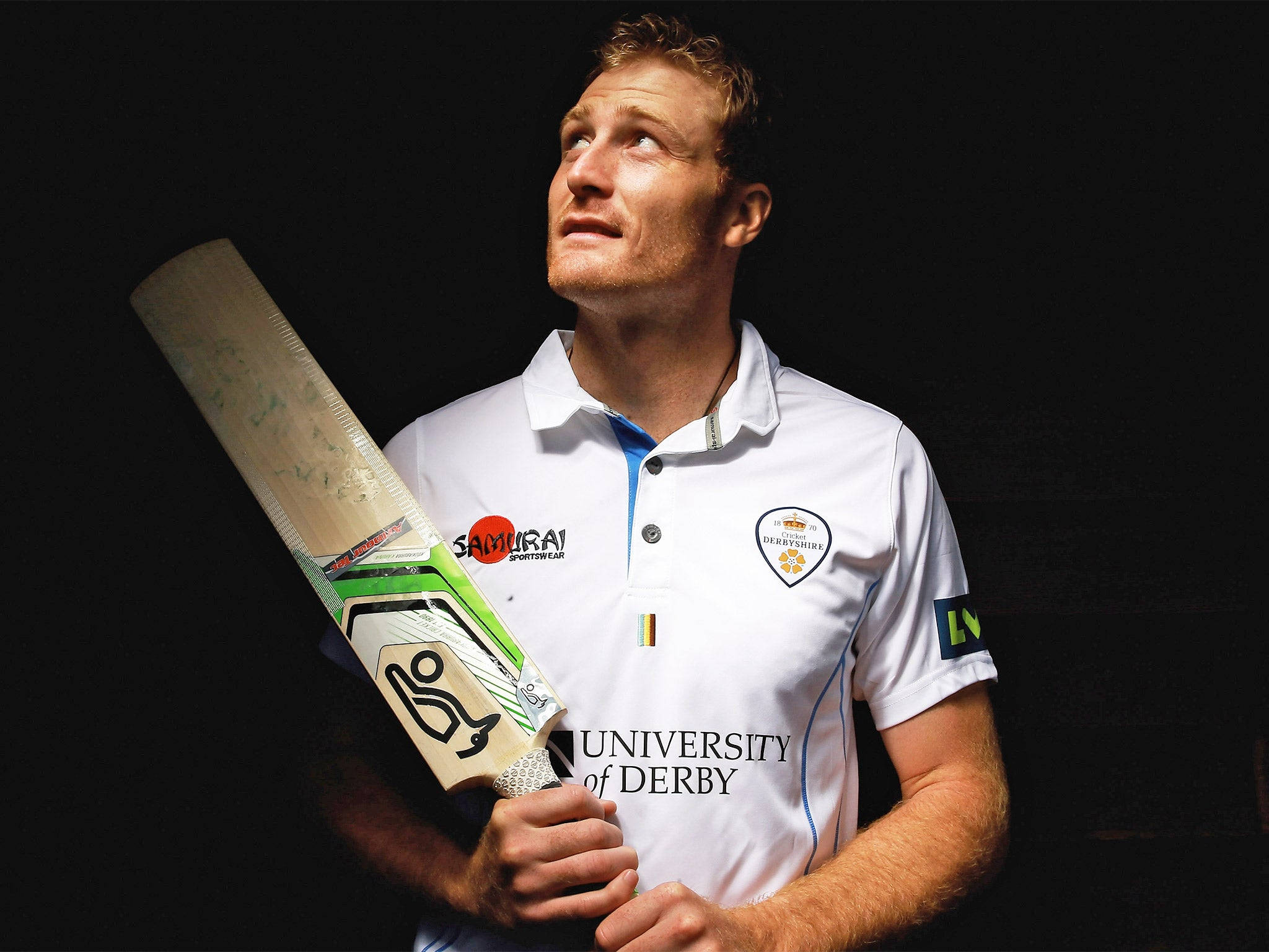 martin guptill 桌布 壁紙 — 一名專注的板球運動員身穿白色德比大學球衣，在黑色背景前手持球棒。