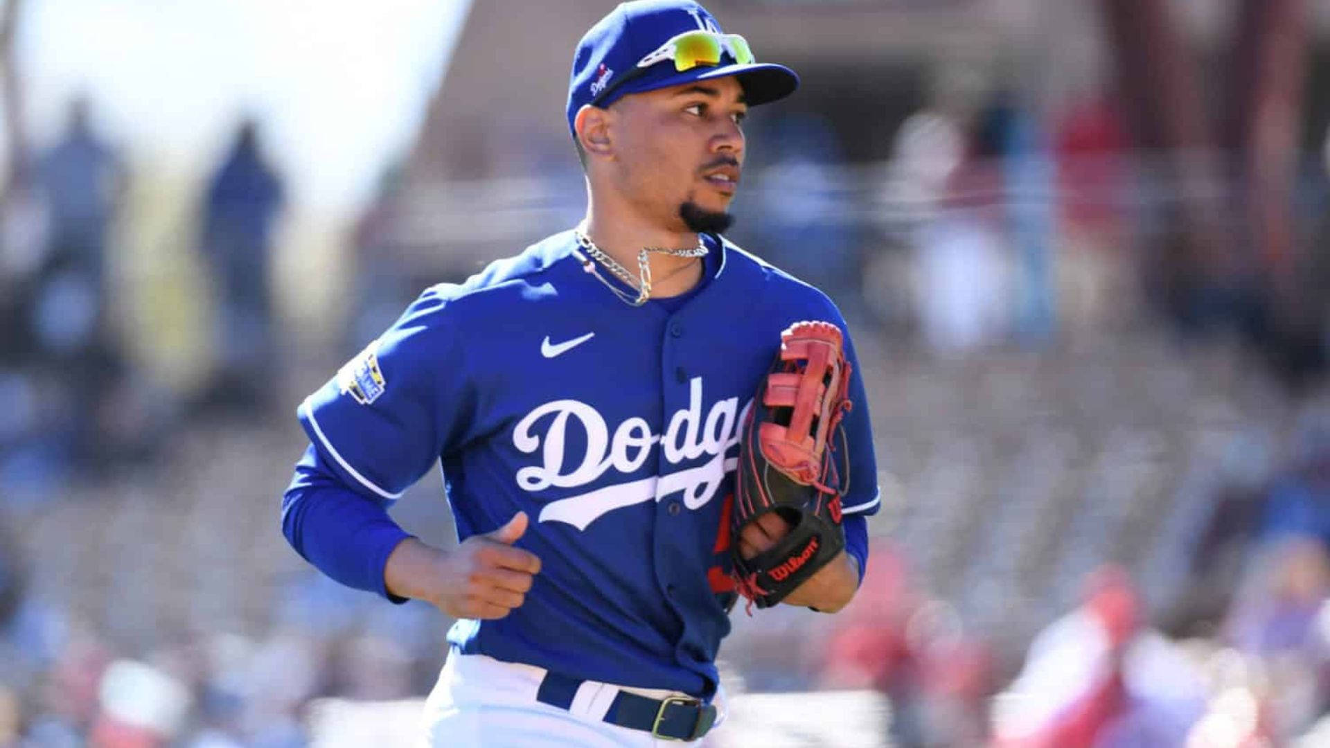 Mookie Betts 桌布 壁紙 — 一名專注的棒球運動員身穿藍色道奇隊制服，在陽光明媚的日間比賽中衝過球場。