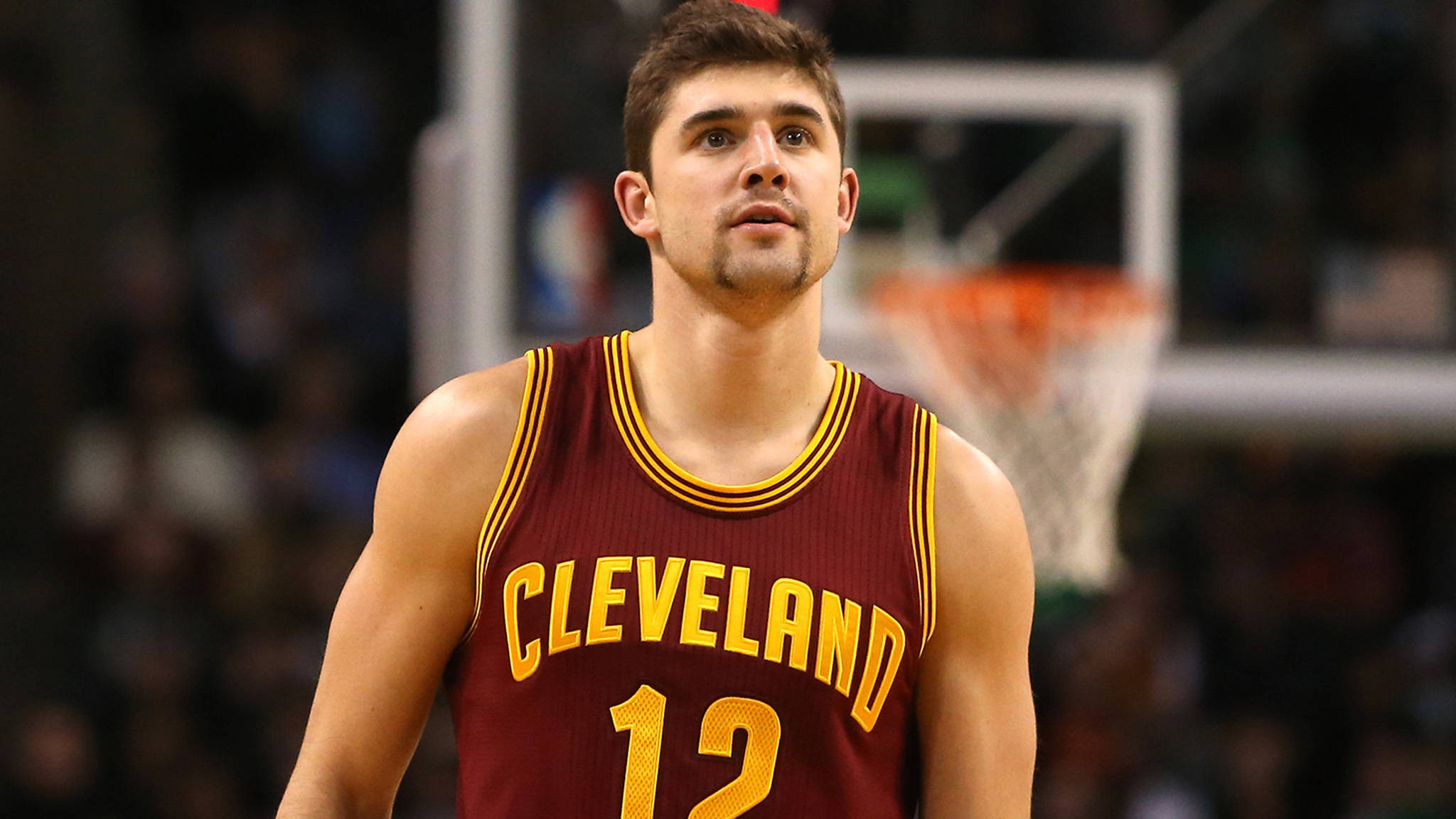 joe harris 桌布 壁紙 — 一名專注的籃球運動員穿著栗色克里夫蘭球衣，號碼12，站在球場上，身後有一個模糊的籃框。