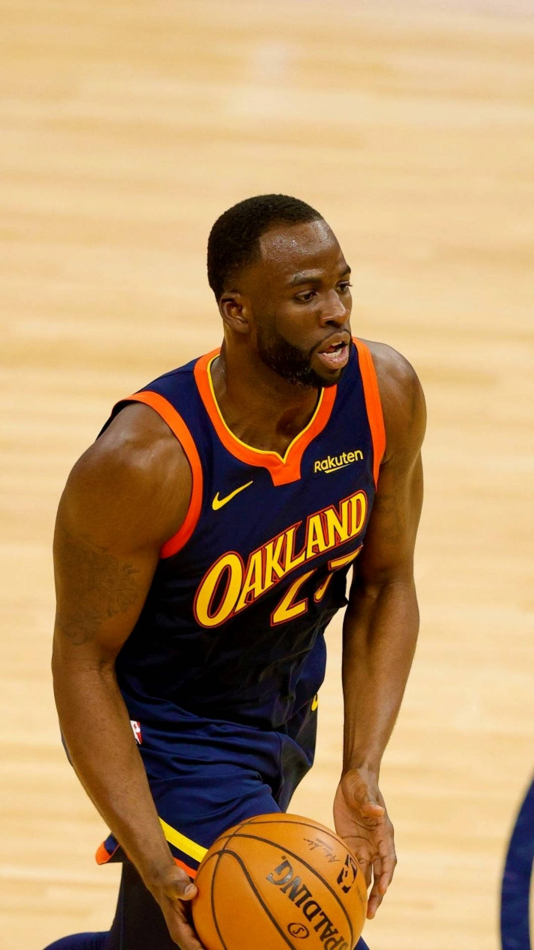 Draymond Green 桌布 壁紙 — 一名專注的籃球運動員身穿奧克蘭球衣，在拋光木地板上運球比賽。