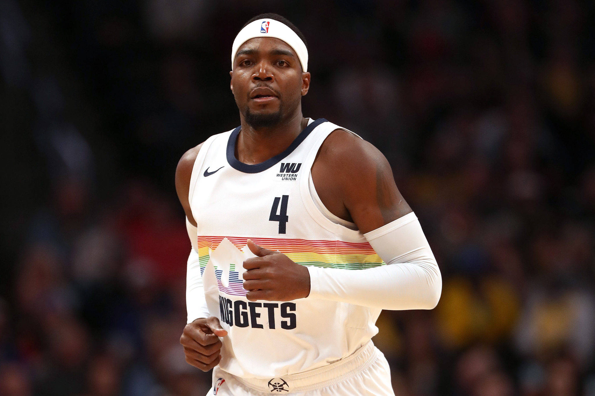 paul millsap 桌布 壁紙 — 一名專注的籃球運動員身穿帶有彩虹條紋的白色丹佛金塊隊球衣，在場館燈光下比賽中奔跑。