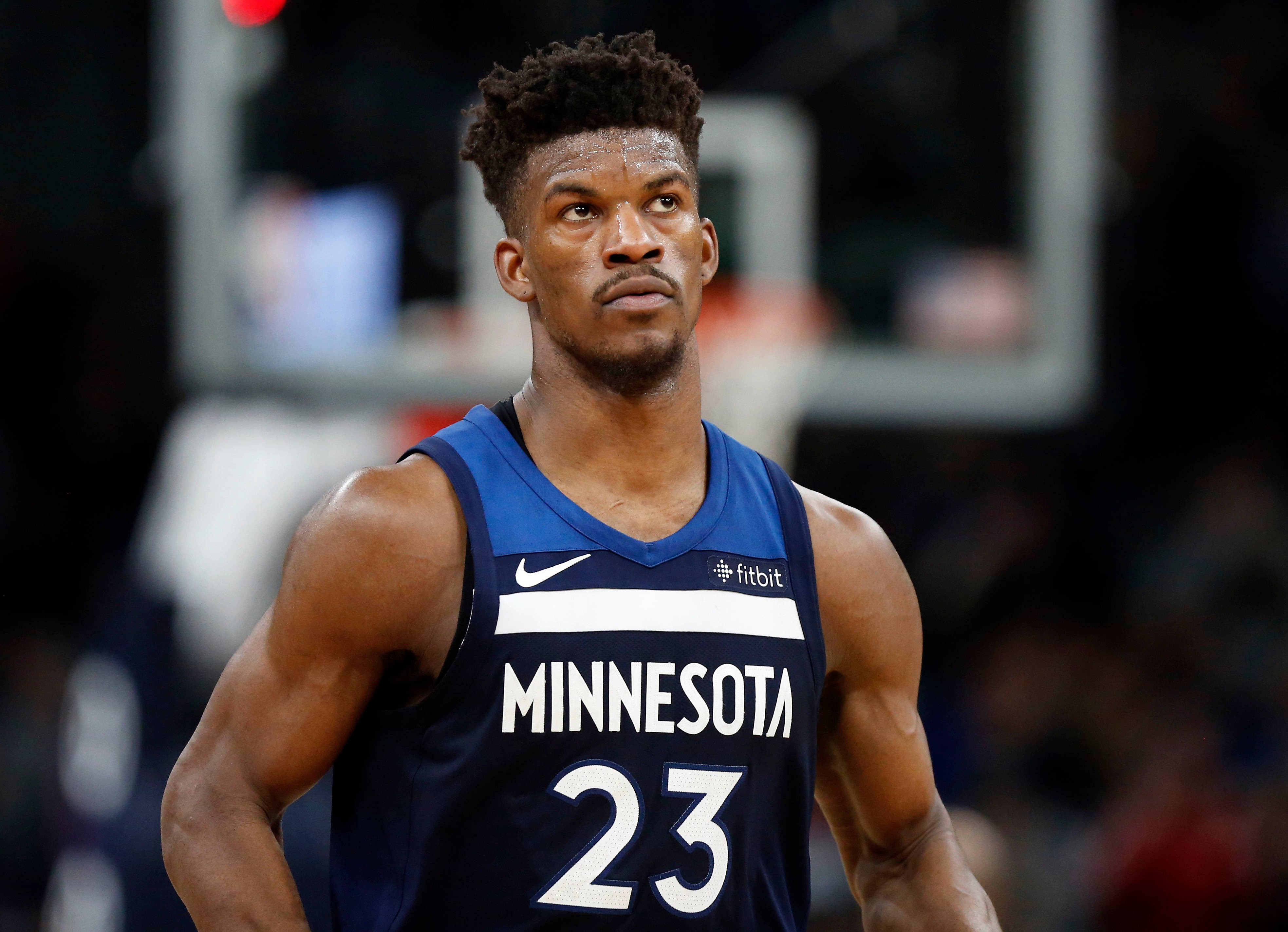 Timberwolves 桌布 壁紙 — 一名專注的籃球運動員身穿明尼蘇達球衣，站在球場上，身後有一個模糊的籃框。