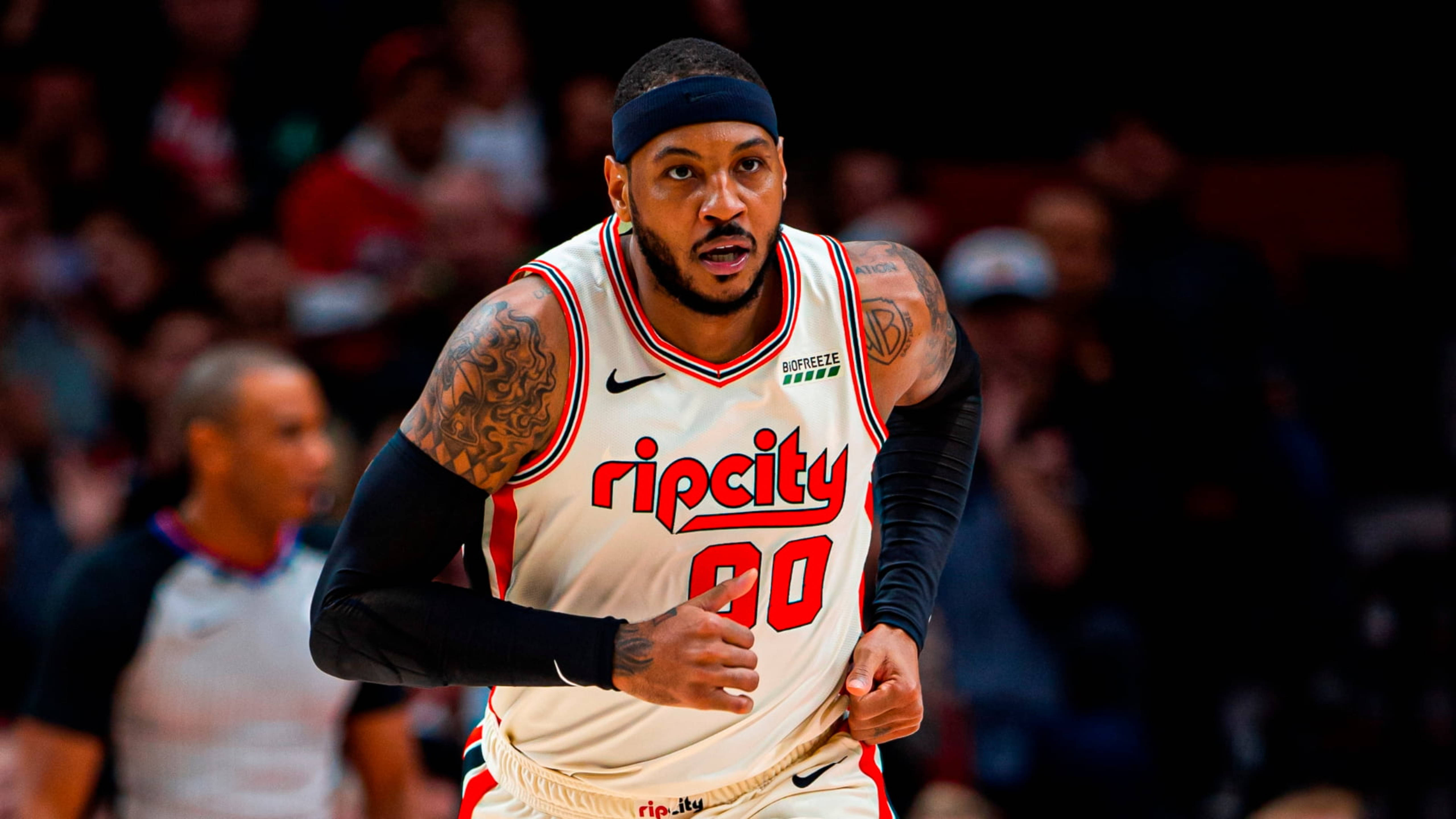 Carmelo 桌布 壁紙 — 一名專注的籃球運動員身穿白色Rip City球衣，帶有紅色點綴，在明亮的場館燈光下激烈奔跑。