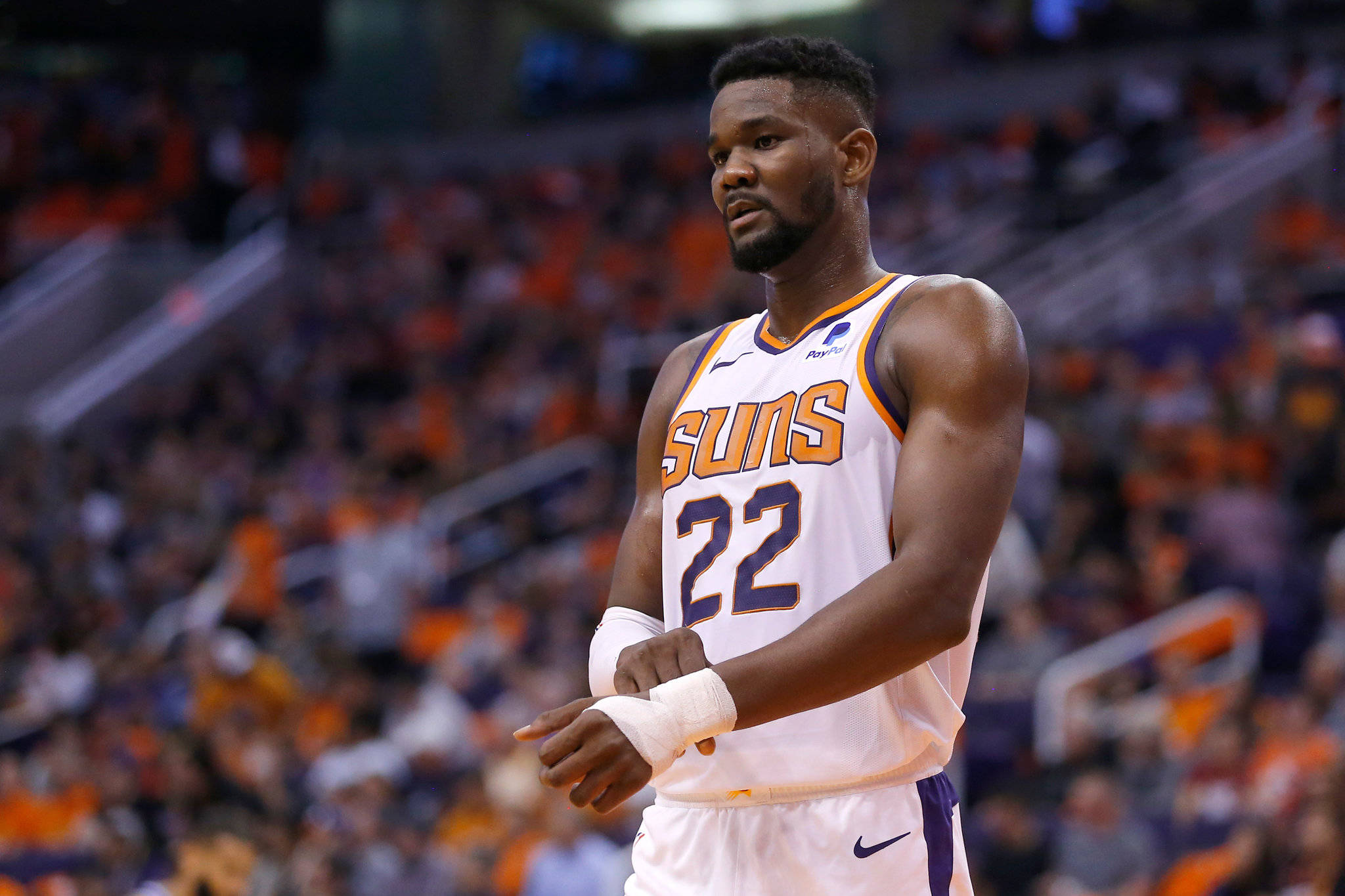 NBA 桌布 壁紙 — 一名專注的籃球運動員身穿白色Suns球衣，號碼22，站在球場上，身後是模糊的橙色人群。