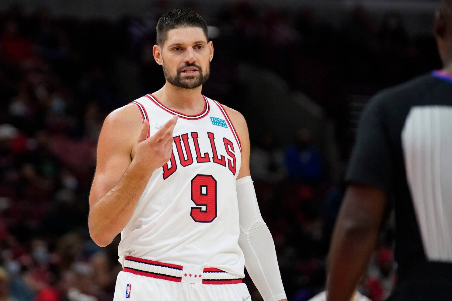 NBA 桌布 壁紙 — 一名專注的籃球運動員身穿白色公牛隊9號球衣，在明亮的場館燈光下比賽中做手勢。