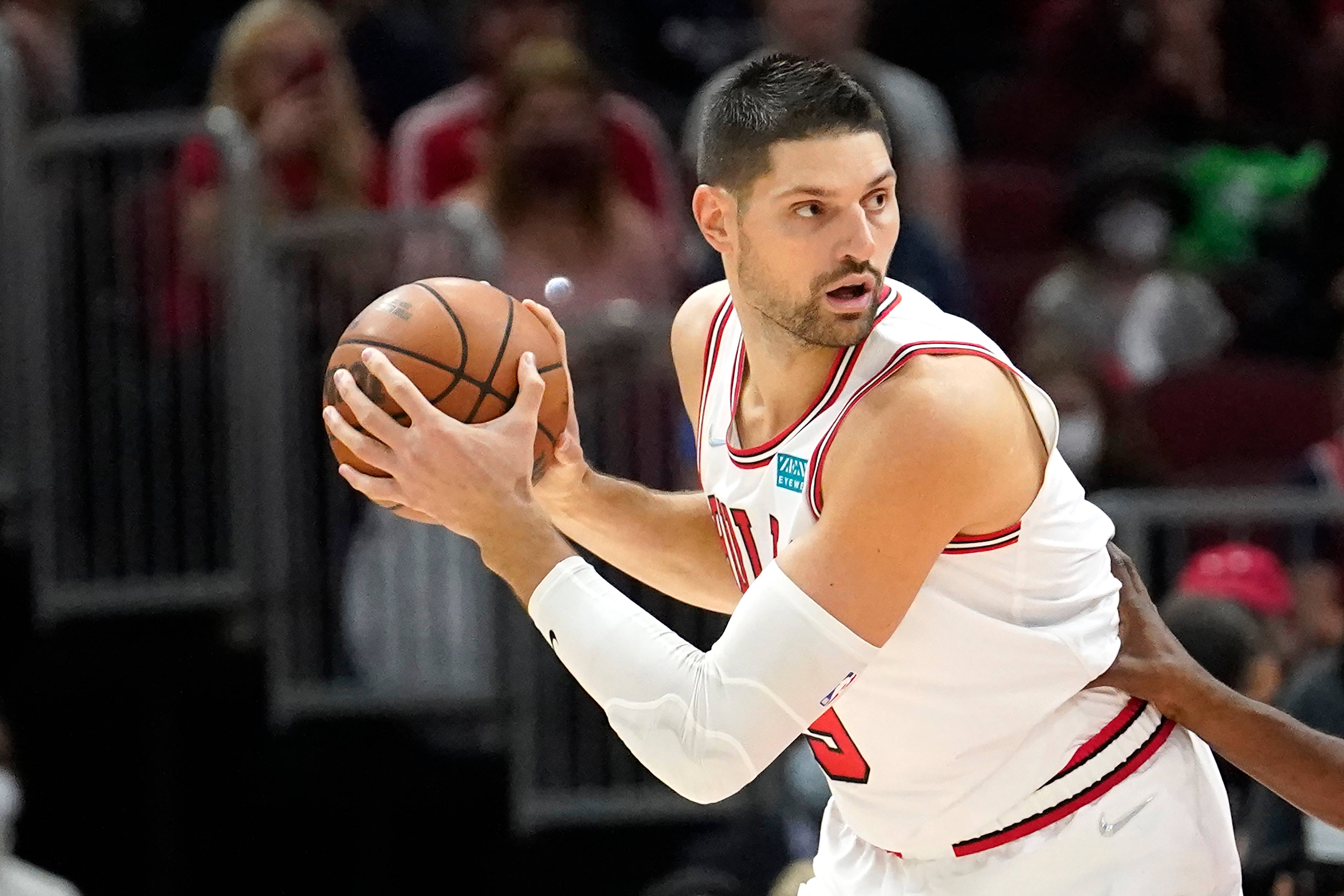 NBA 桌布 壁紙 — 一名專注的籃球運動員身穿白色球衣，在燈光明亮的球場上運球，同時被防守。