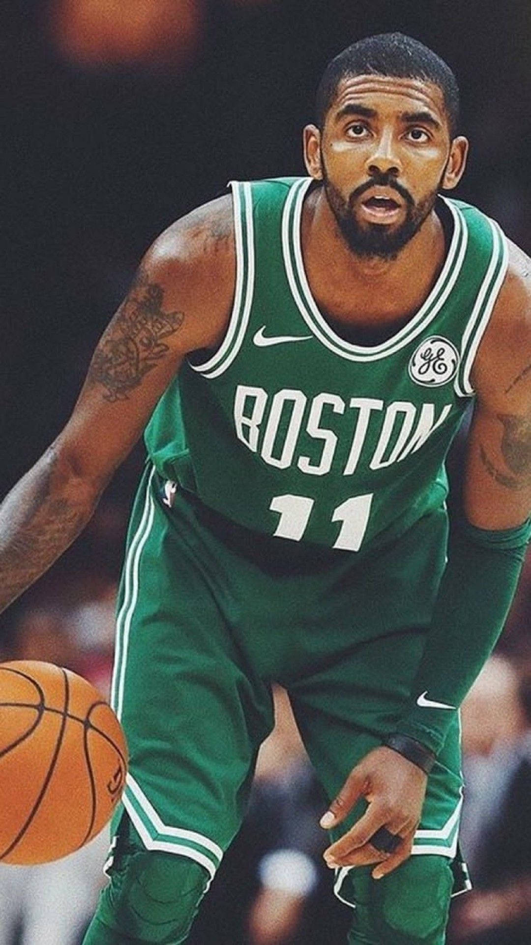 Kyrie 桌布 壁紙 — 一名專注的籃球運動員身穿綠色波士頓球衣，在明亮的場館燈光下於比賽中運球。