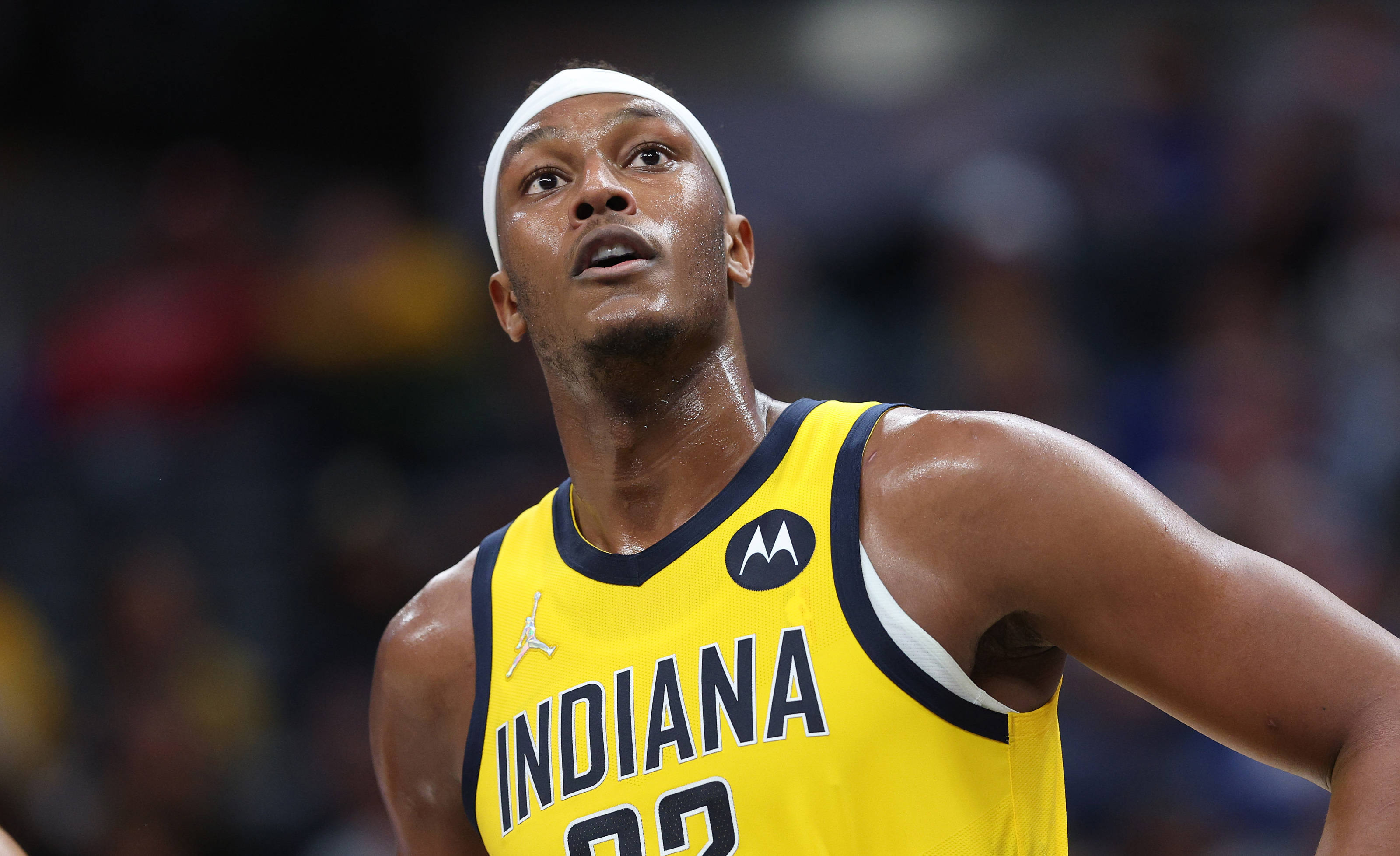 myles turner 桌布 壁紙 — 一名專注的籃球運動員身穿黃色印第安納球衣，在明亮的場館燈光下於激烈的比賽中向上看。