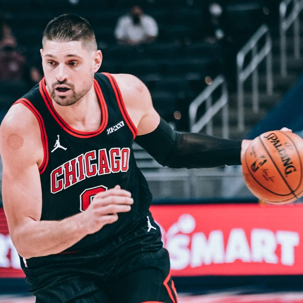 NBA 桌布 壁紙 — 一名專注的籃球運動員身穿黑色芝加哥球衣，在明亮的場館燈光下於比賽中激烈運球。