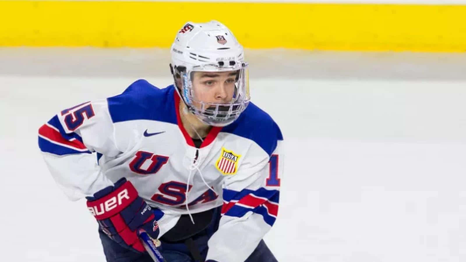 hockey 桌布 壁紙 — 一名專注的美國冰球運動員身穿白、藍、紅色裝備，帶著強烈決心蹲在冰場上。