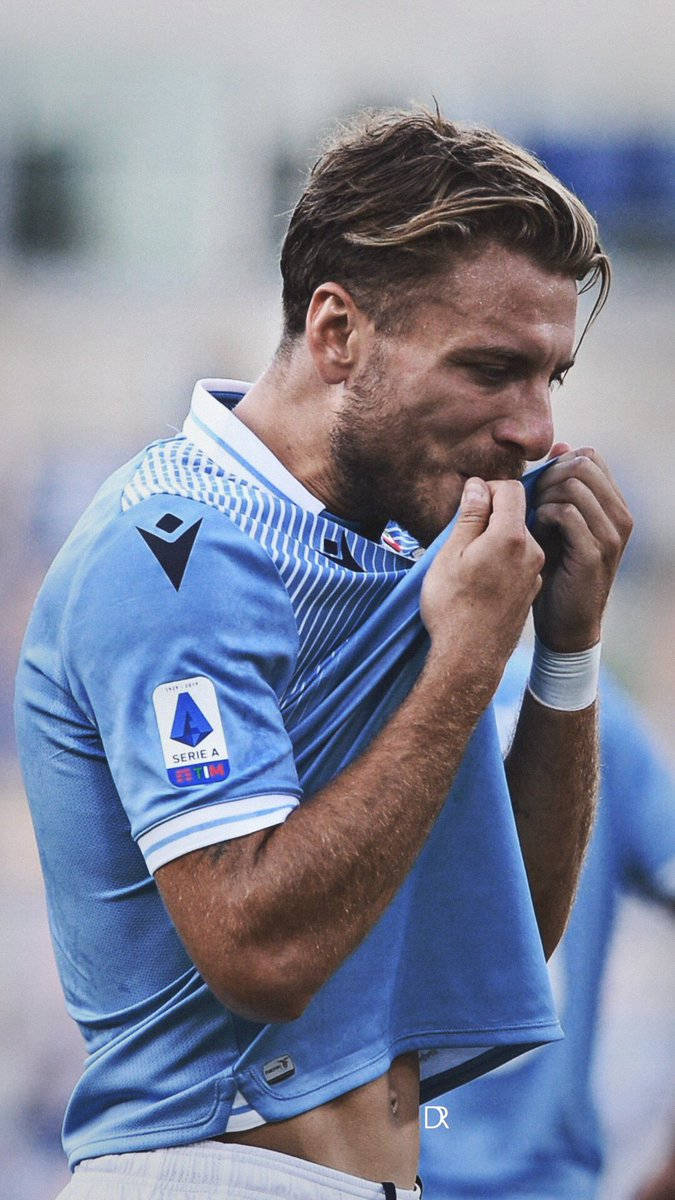 ciro immobile 桌布 壁紙 — 一名專注的足球員身穿淺藍色球衣，在球場燈光下比賽時咬住衣袖。