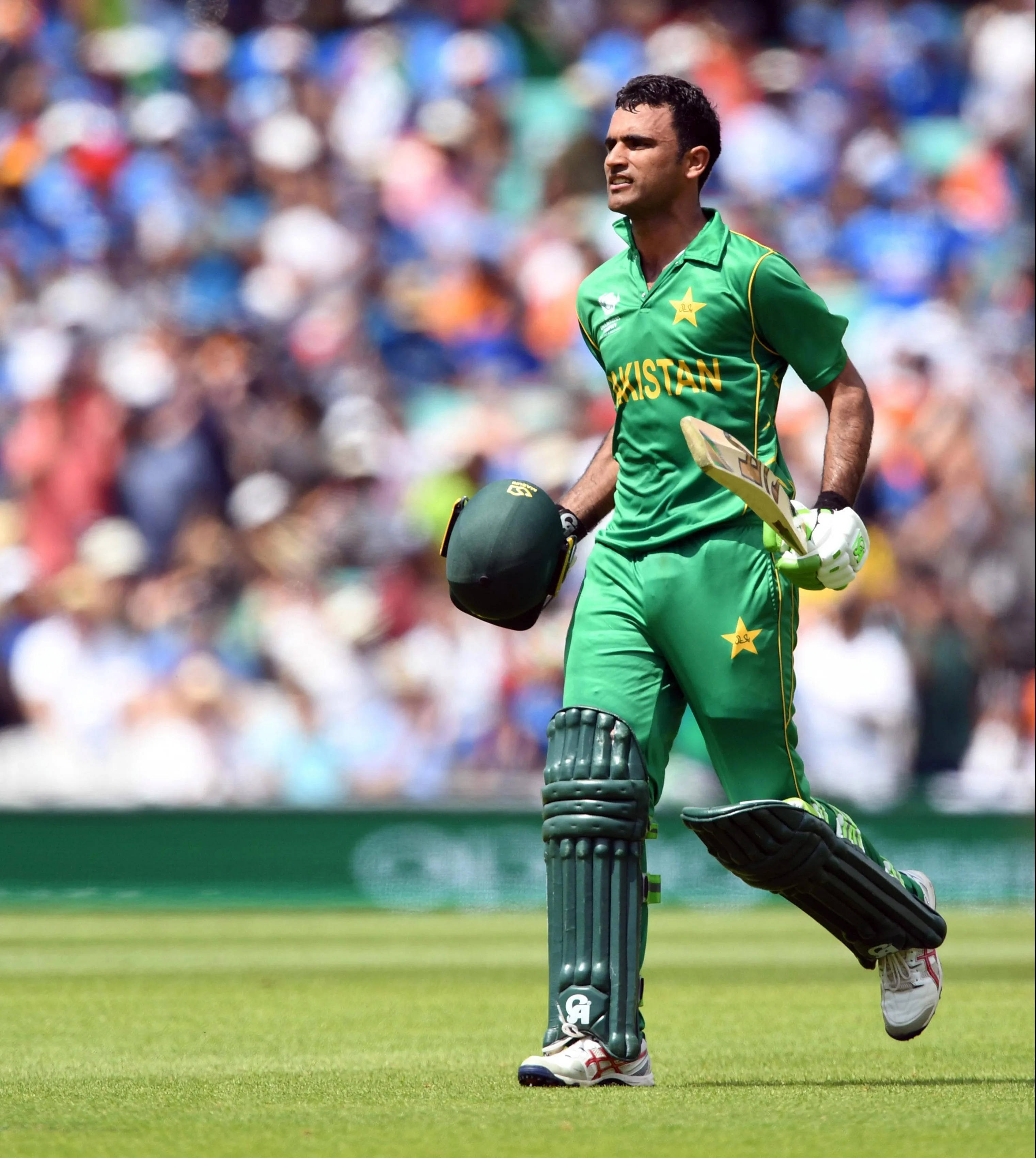 Fakhar Zaman 桌布 壁紙 — 一名巴基斯坦板球運動員穿著綠色制服，在明亮的日光下拿著球棒和頭盔離開球場。