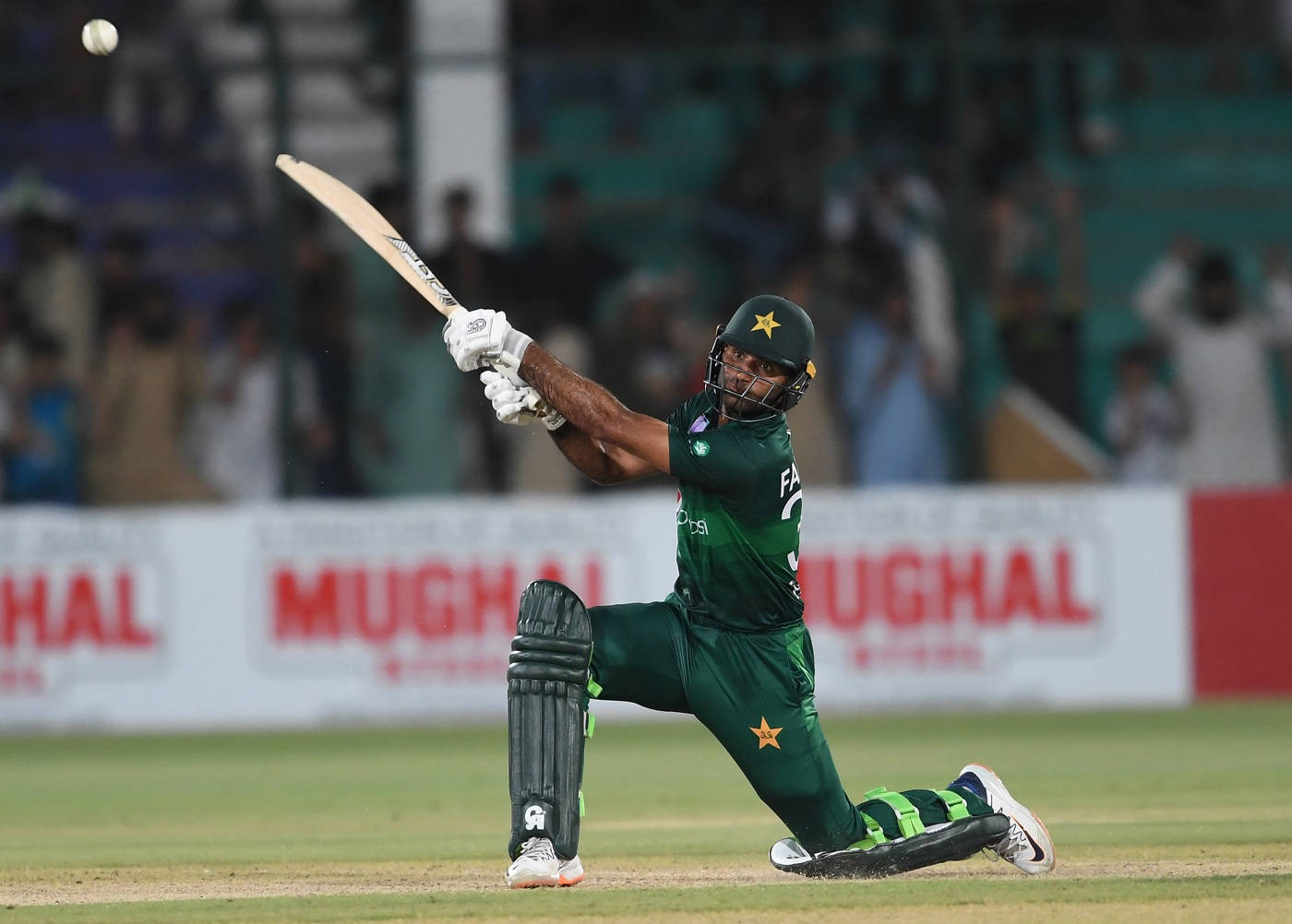 Fakhar Zaman 桌布 壁紙 — 一名巴基斯坦板球運動員身穿綠色制服，在體育場燈光下的夜間比賽中強力揮拍擊球。
