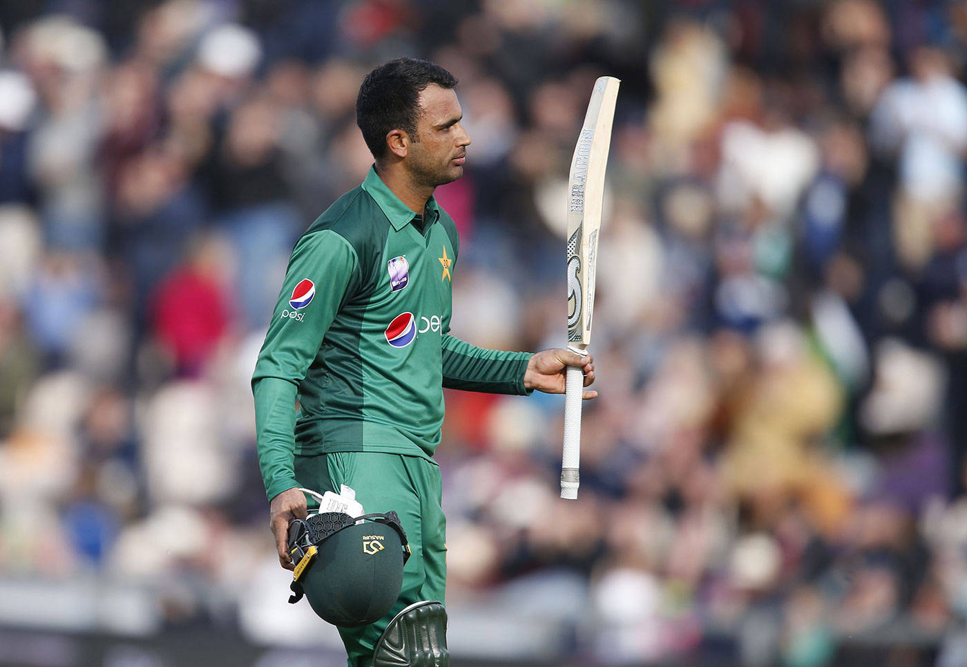 Fakhar Zaman 桌布 壁紙 — 一名巴基斯坦板球運動員身穿綠色制服，手持球棒和頭盔，在日間比賽中離場。