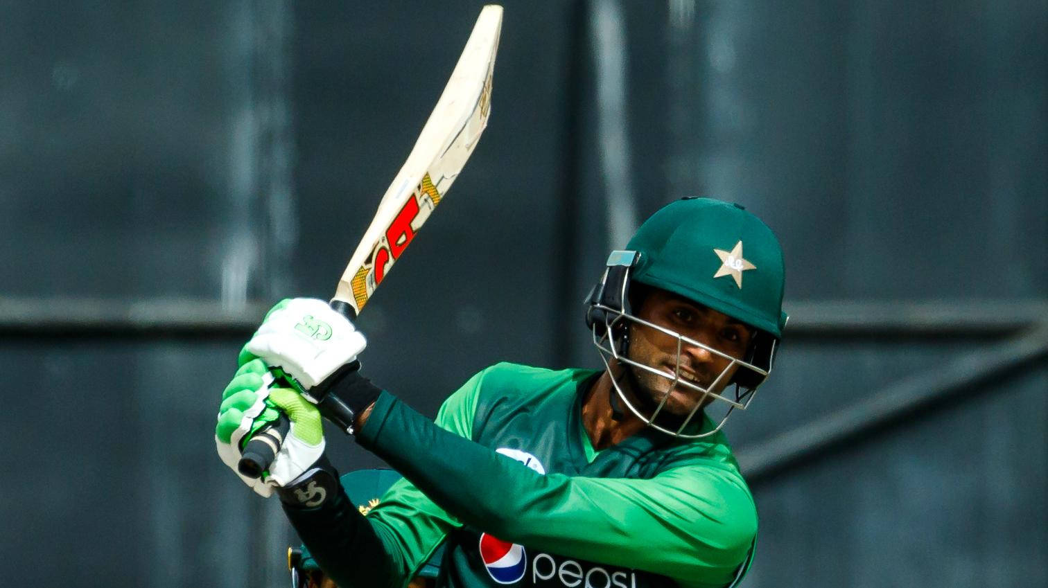 Fakhar Zaman 桌布 壁紙 — 一名巴基斯坦板球運動員身穿綠色制服，在深色背景下全神貫注地揮動球棒。