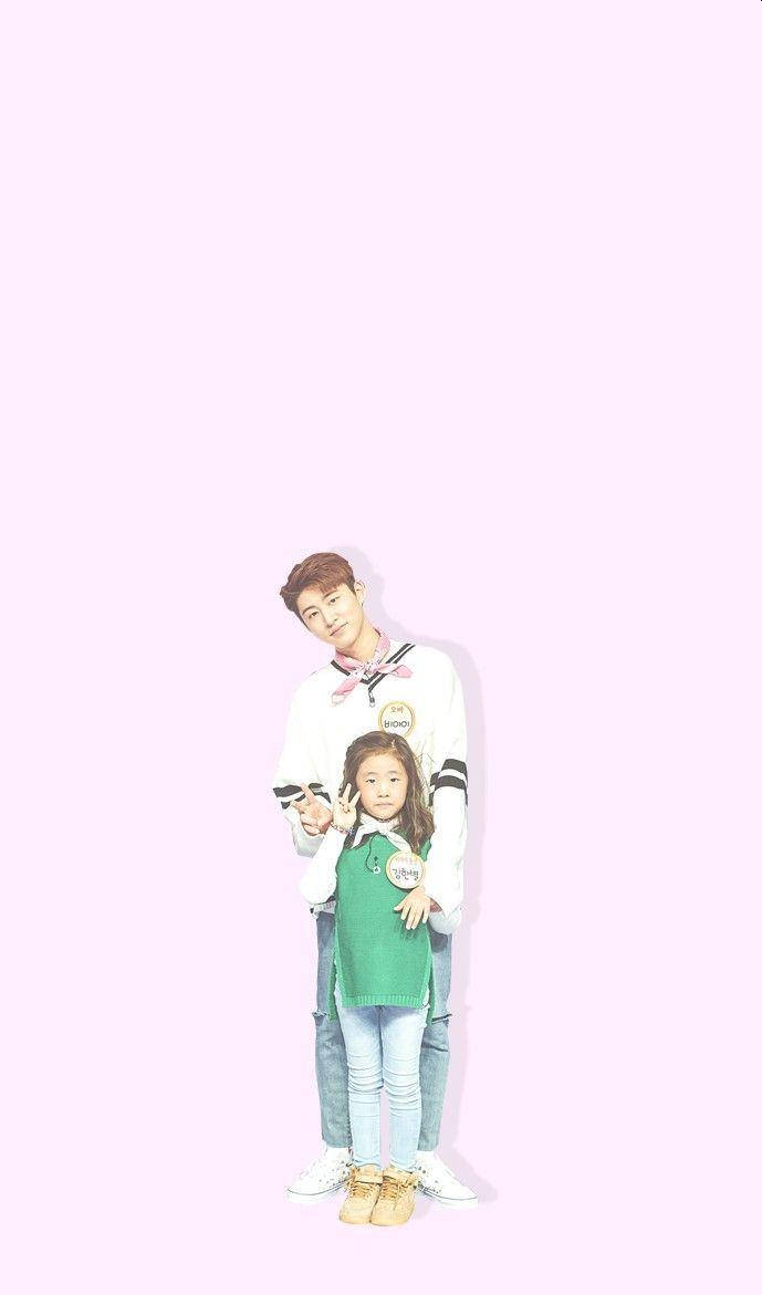 kim hanbin 桌布 壁紙 — 一名年輕男子和女孩在柔和的粉紅色背景前一起擺姿勢，兩人都做出和平手勢，表情愉快。