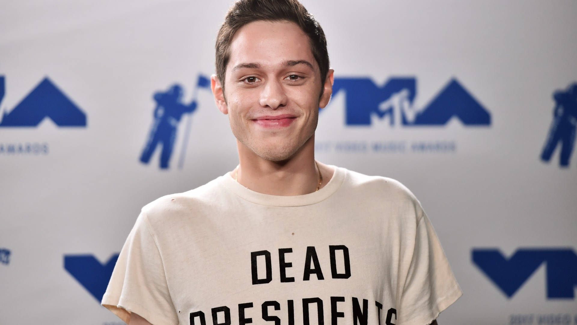 Pete Davidson 桌布 壁紙 — 一名年輕男子在MTV活動中穿著印有「DEAD PRESIDENTS」字樣的米色T恤對著鏡頭微笑。