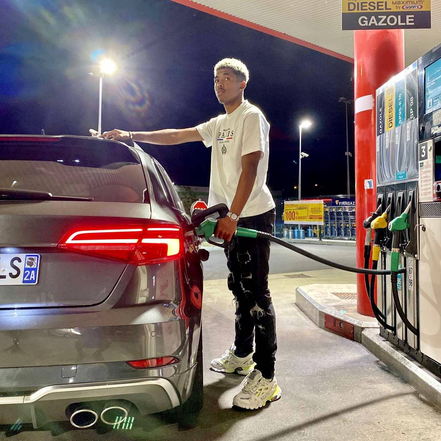 Celebrity 桌布 壁紙 — 一名年輕男子在夜晚明亮的加油站燈光下為銀色SUV加注柴油。