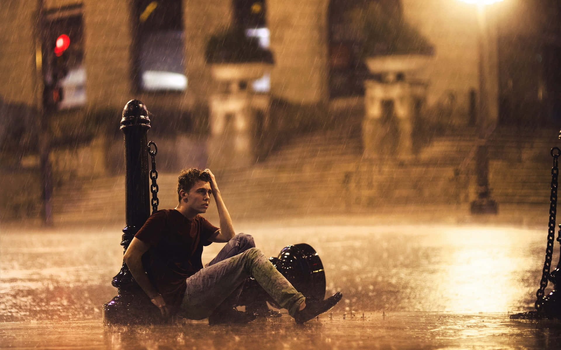 Sad Face 桌布 壁紙 — 一名年輕男子在暴雨期間獨自坐在城市環境中路燈下的洪水中。
