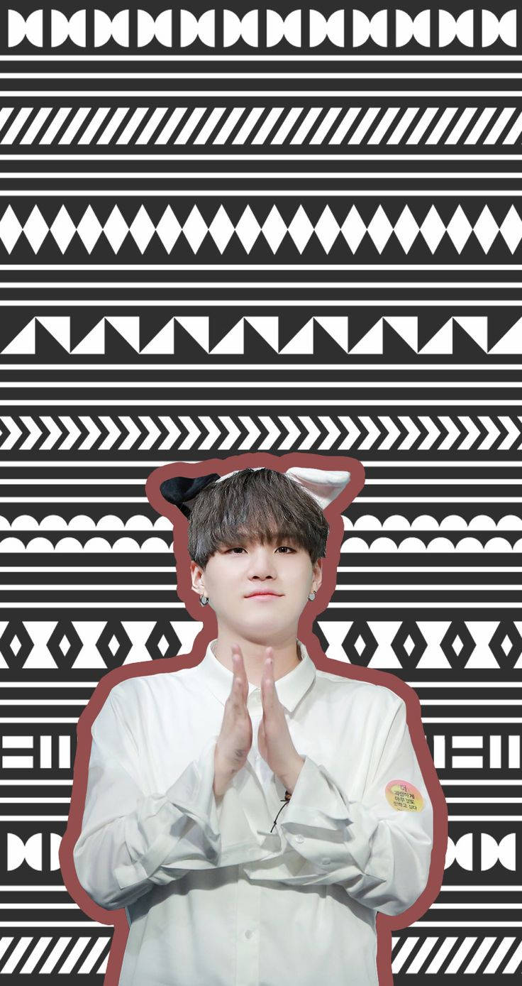 Cute Bts 桌布 壁紙 — 一名年輕男子戴著貓耳，雙手合十，背景為大膽的黑白幾何圖案。