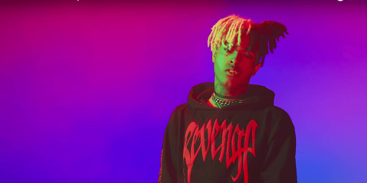 XXXTENTACION 桌布 壁紙 — 一名年輕男子染著螢光色辮子，在紫色和粉紅色的漸變背景前凝視著。