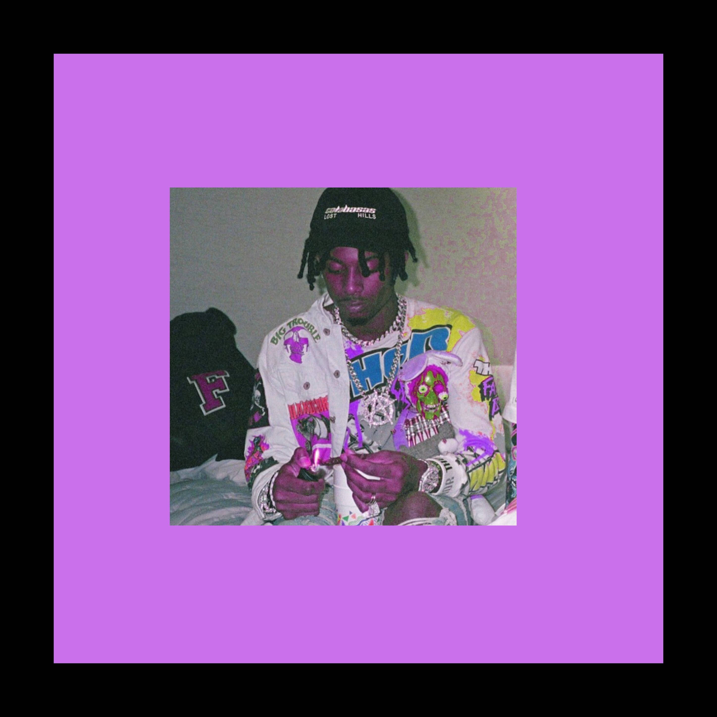 Carti 桌布 壁紙 — 一名年輕男子留著辮子頭，戴黑色帽子，坐在床上，身穿色彩繽紛的圖案外套和多條鏈條，手持一個小物件。