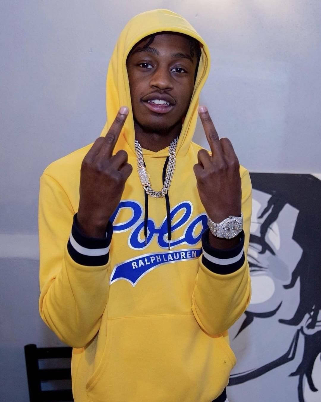 Lil Tjay 桌布 壁紙 — 一名年輕男子穿著亮黃色Ralph Lauren連帽衫，豎起雙手中指，戴著粗鏈條和鑲鑽手錶。