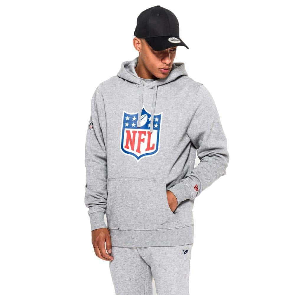 NFL 桌布 壁紙 — 一名年輕男子穿著灰色NFL連帽衫和配套運動褲，一手插袋，在純白背景前擺姿勢。