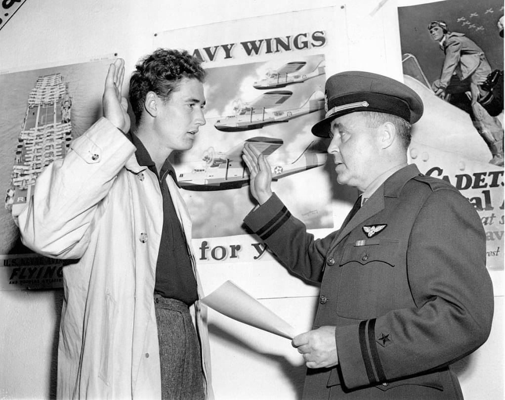Ted Williams 桌布 壁紙 — 一名年輕男子舉起右手，海軍軍官在航空海報旁進行宣誓。
