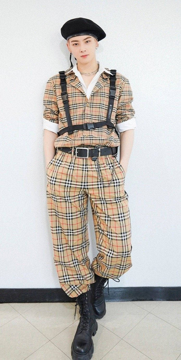 Eunwoo 桌布 壁紙 — 一名年輕男子身穿米色格紋連身褲，搭配黑色吊帶和靴子，自信地站在純白牆壁前。