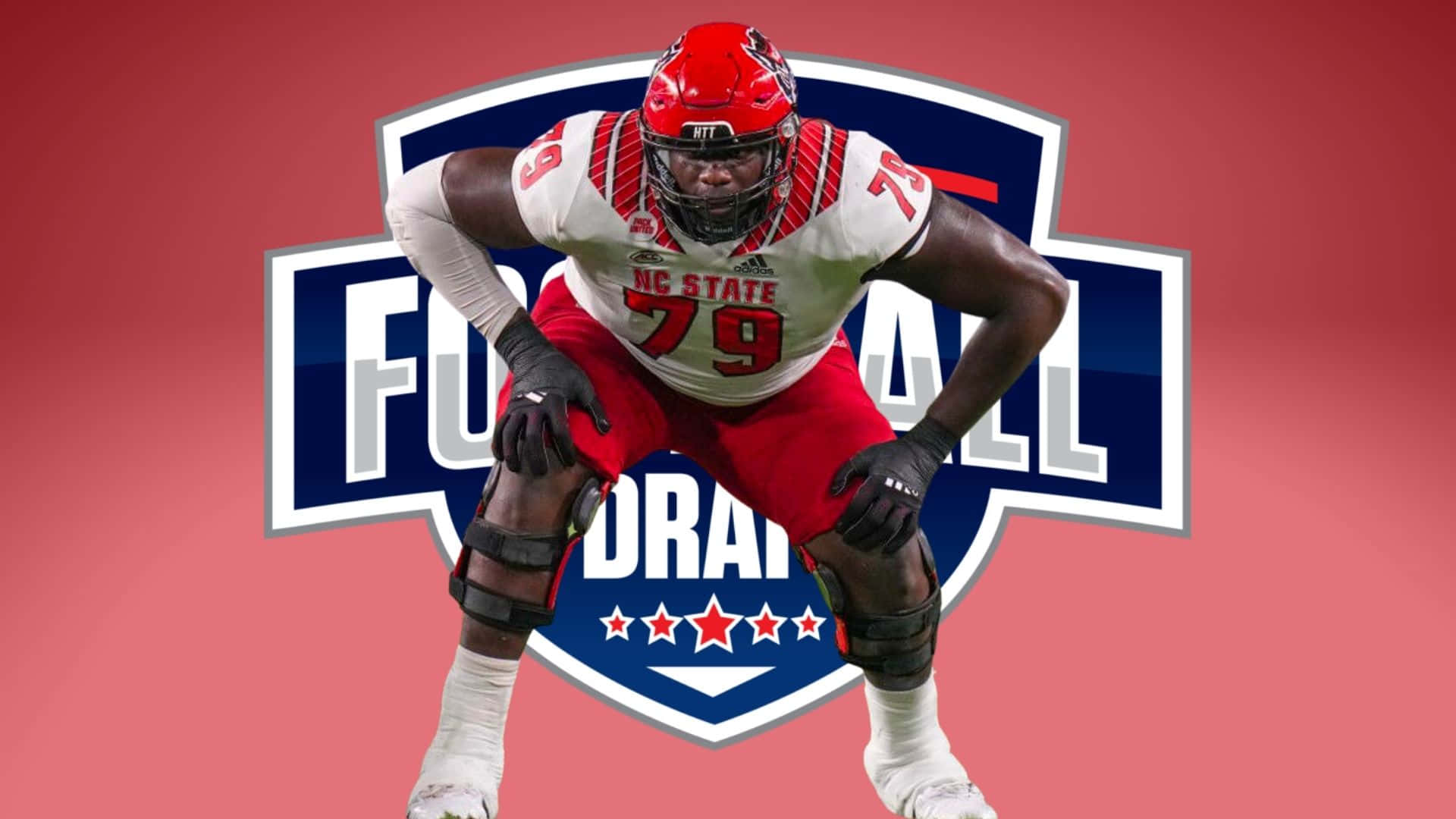 足球 桌布 壁紙 — 一名強大的NC State足球運動員身穿紅白裝備，在帶有'Football Draft'標誌的醒目紅色背景上動態蹲伏。