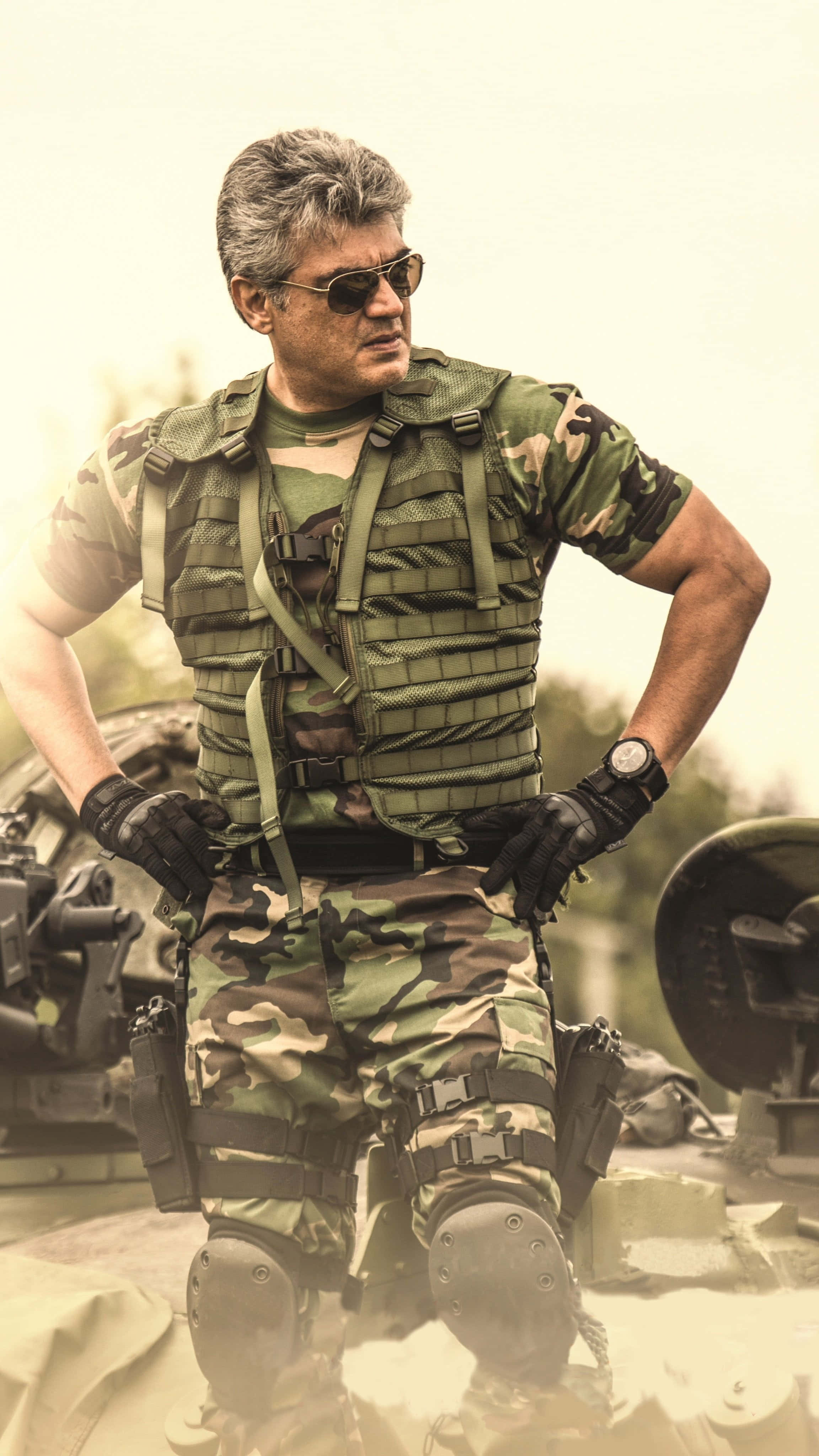印度軍隊 桌布 壁紙 — 一名強悍的士兵身穿全套迷彩裝備，雙手叉腰，自信地站在軍用坦克旁。