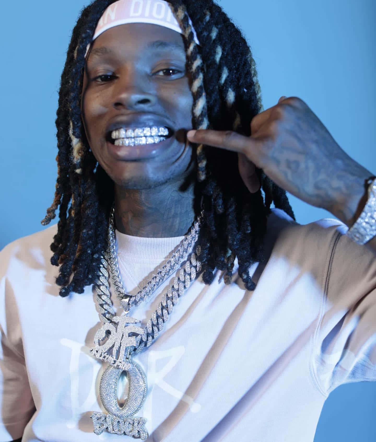 編著辮子頭髮、戴著鑽石牙套的男子指著自己的牙齒。 — King Von 壁紙
