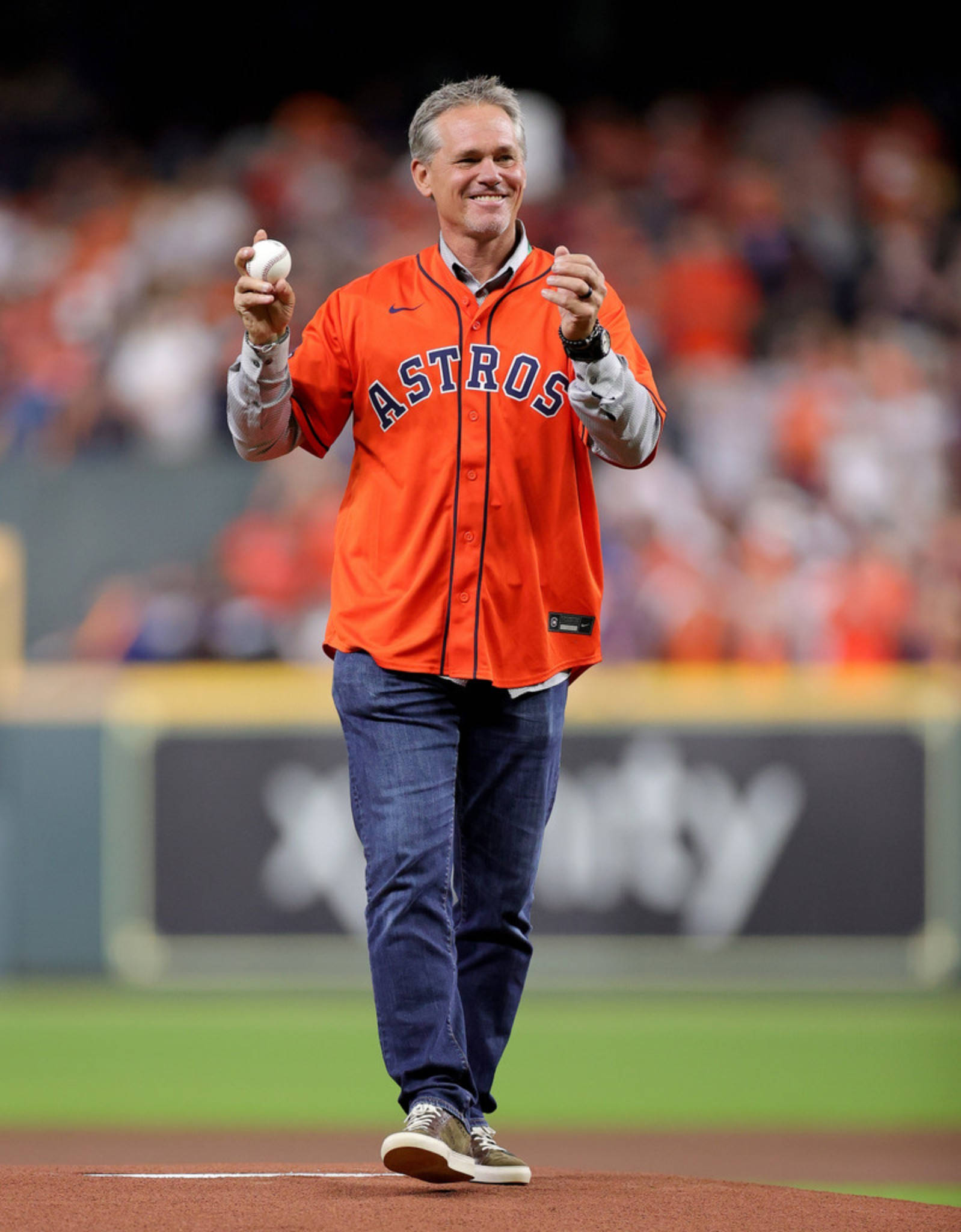 Craig Biggio 桌布 壁紙 — 一名微笑的男子穿著橙色Astros球衣，在夜間球場上拿著棒球向球迷揮手。