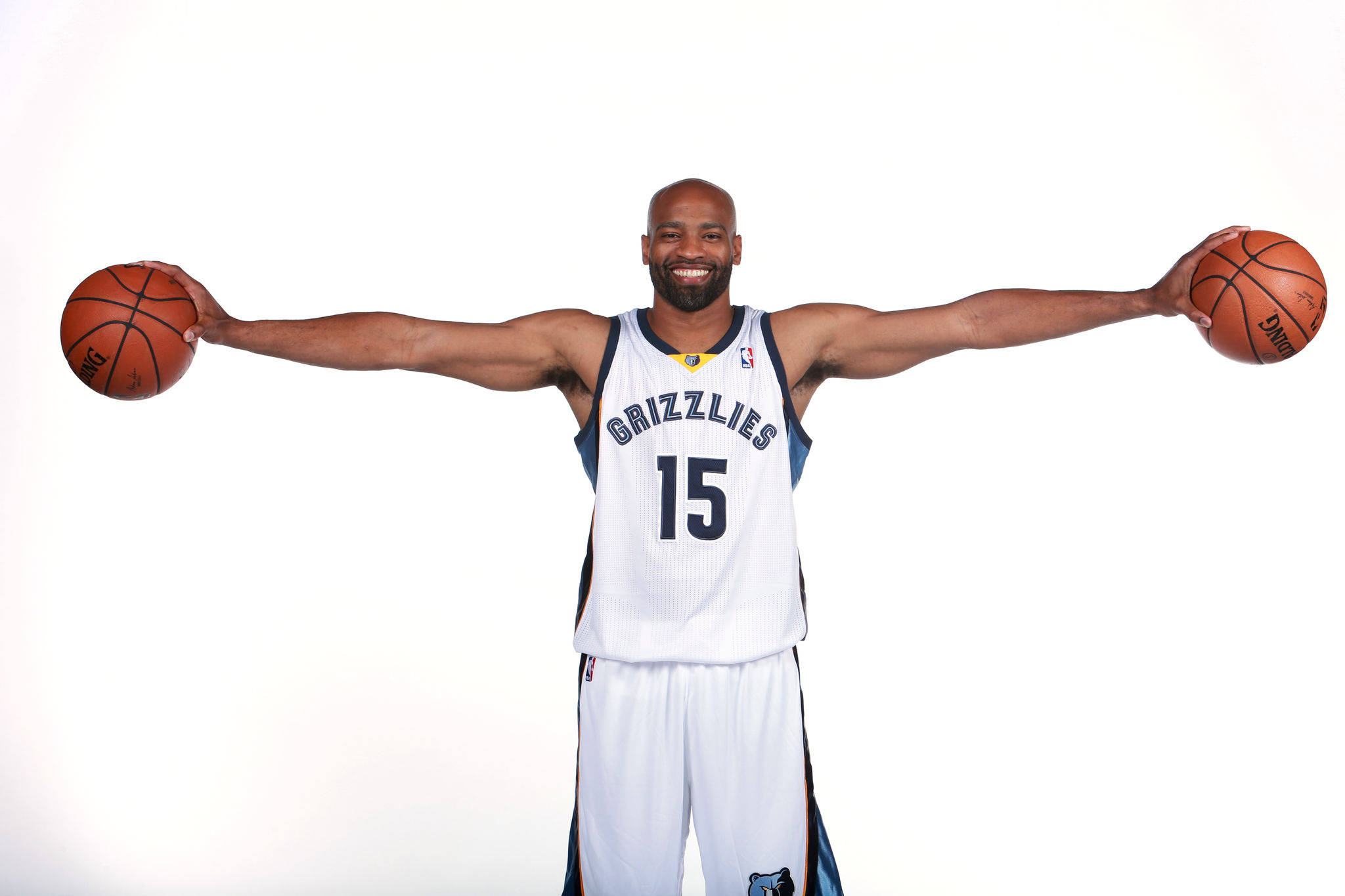 NBA 桌布 壁紙 — 一名微笑的籃球運動員身穿灰熊隊球衣，雙臂張開，每隻手各持一個球，背景為純白色。