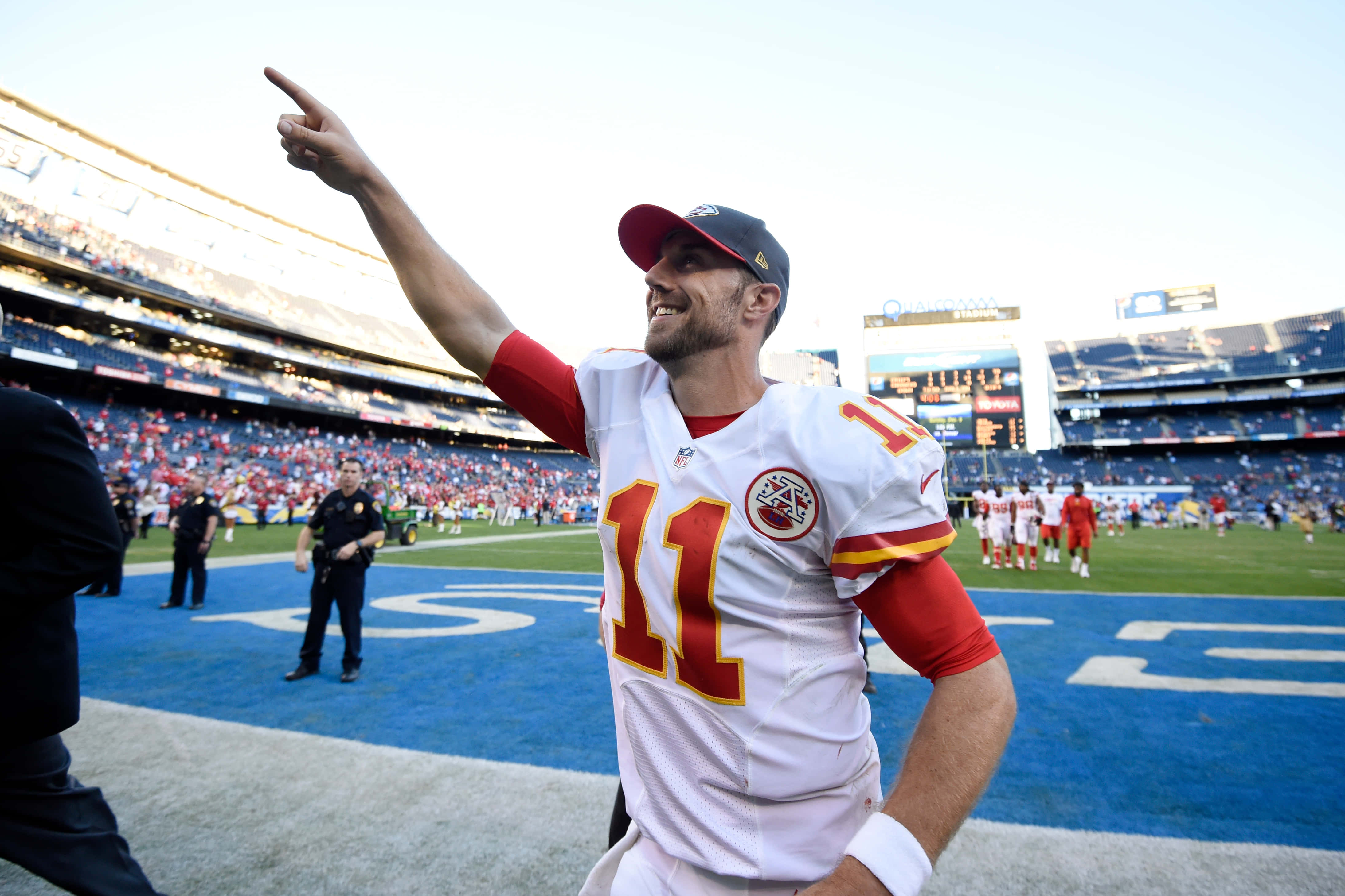 Football Players 桌布 壁紙 — 一名微笑的足球員身穿白色球衣，背號11，站在球場上，背景有球迷，手指向上指。